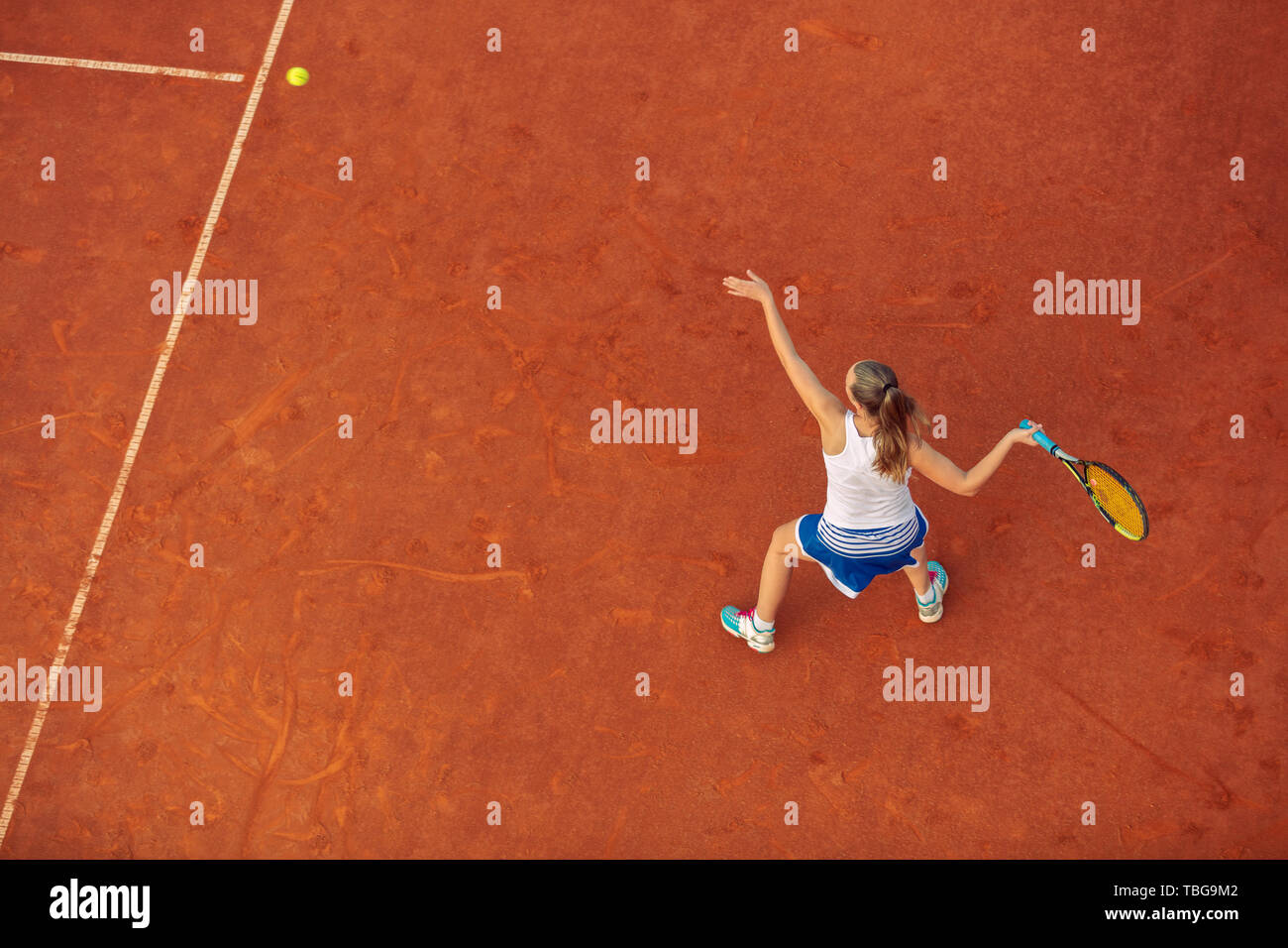 Ripresa aerea di una femmina di giocatore di tennis su una corte durante la partita. Giovane donna giocando a tennis.ad alto angolo di visione. Foto Stock