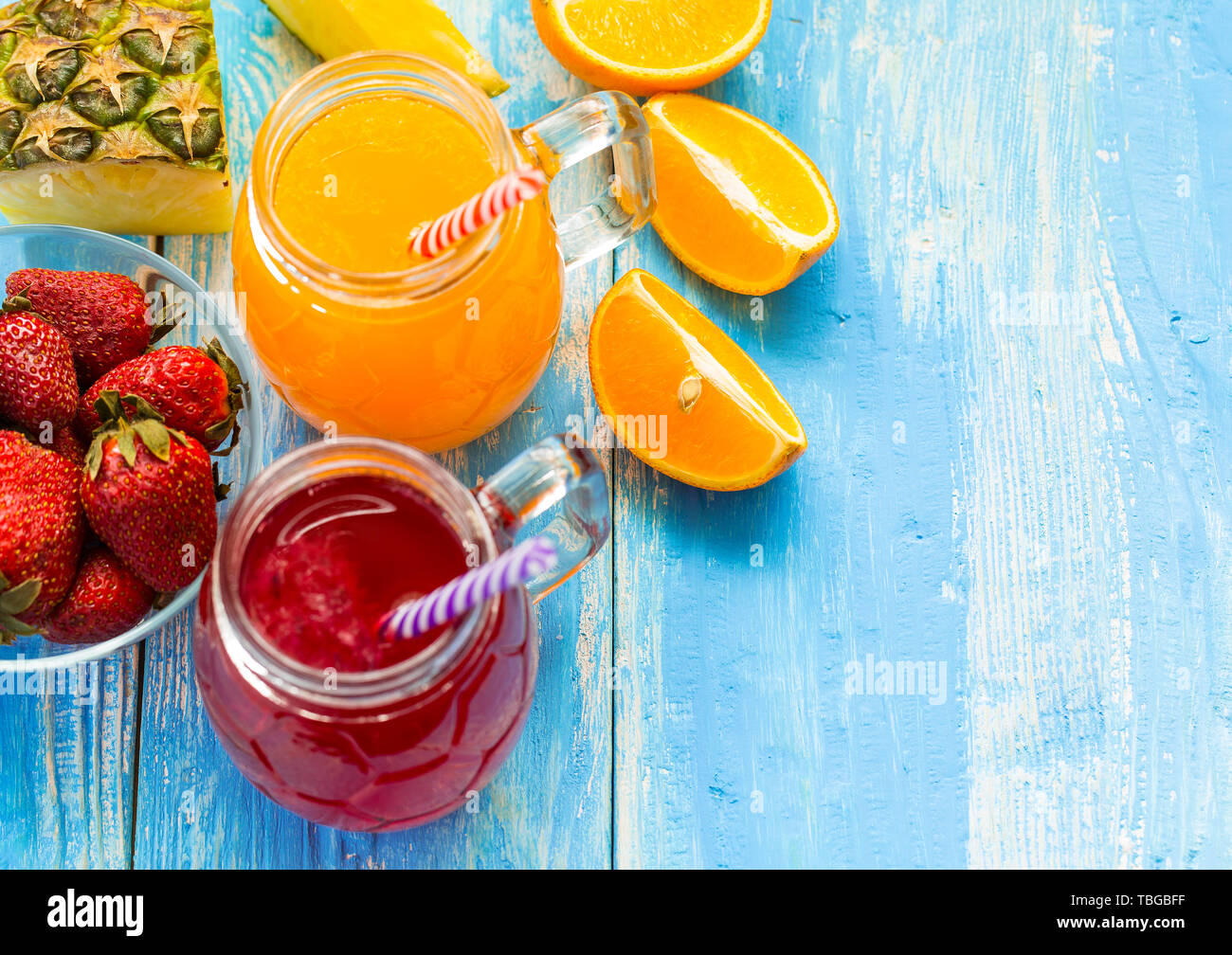 Ananas fresco e frullato fragole in bicchieri con frutti su un blu rustico in legno sfondo. Mescolate fresco drink estivo bello bere durante una Foto Stock