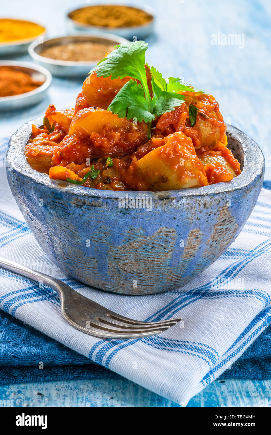 Bombay, aloo - Indiano patate speziate con salsa di pomodoro guarnita con foglie di coriandolo fresco. Foto Stock