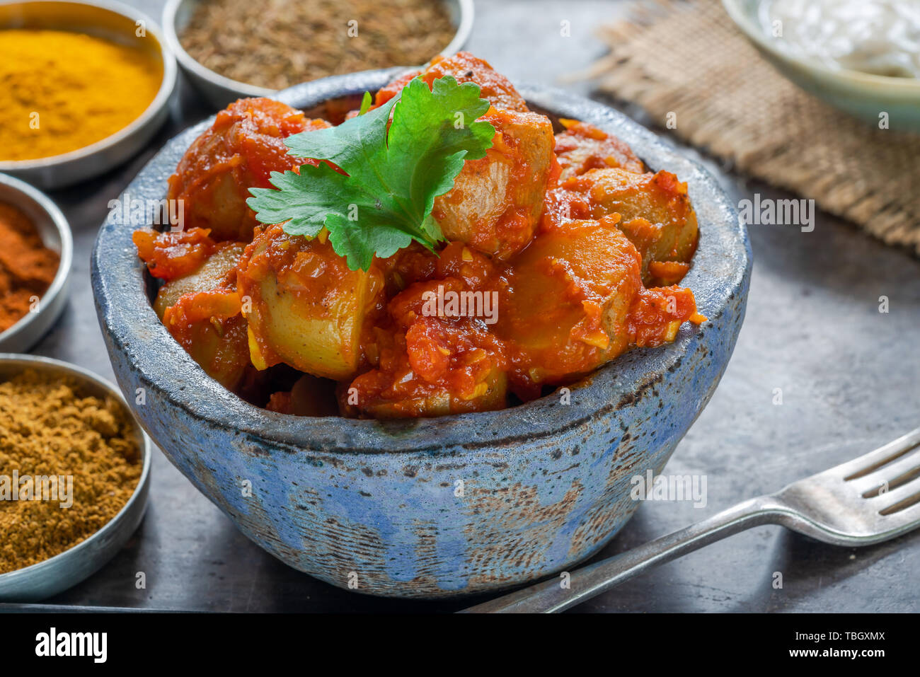 Bombay, aloo - Indiano patate speziate con salsa di pomodoro e coniati yogurt, guarnite con foglie di coriandolo fresco. Foto Stock