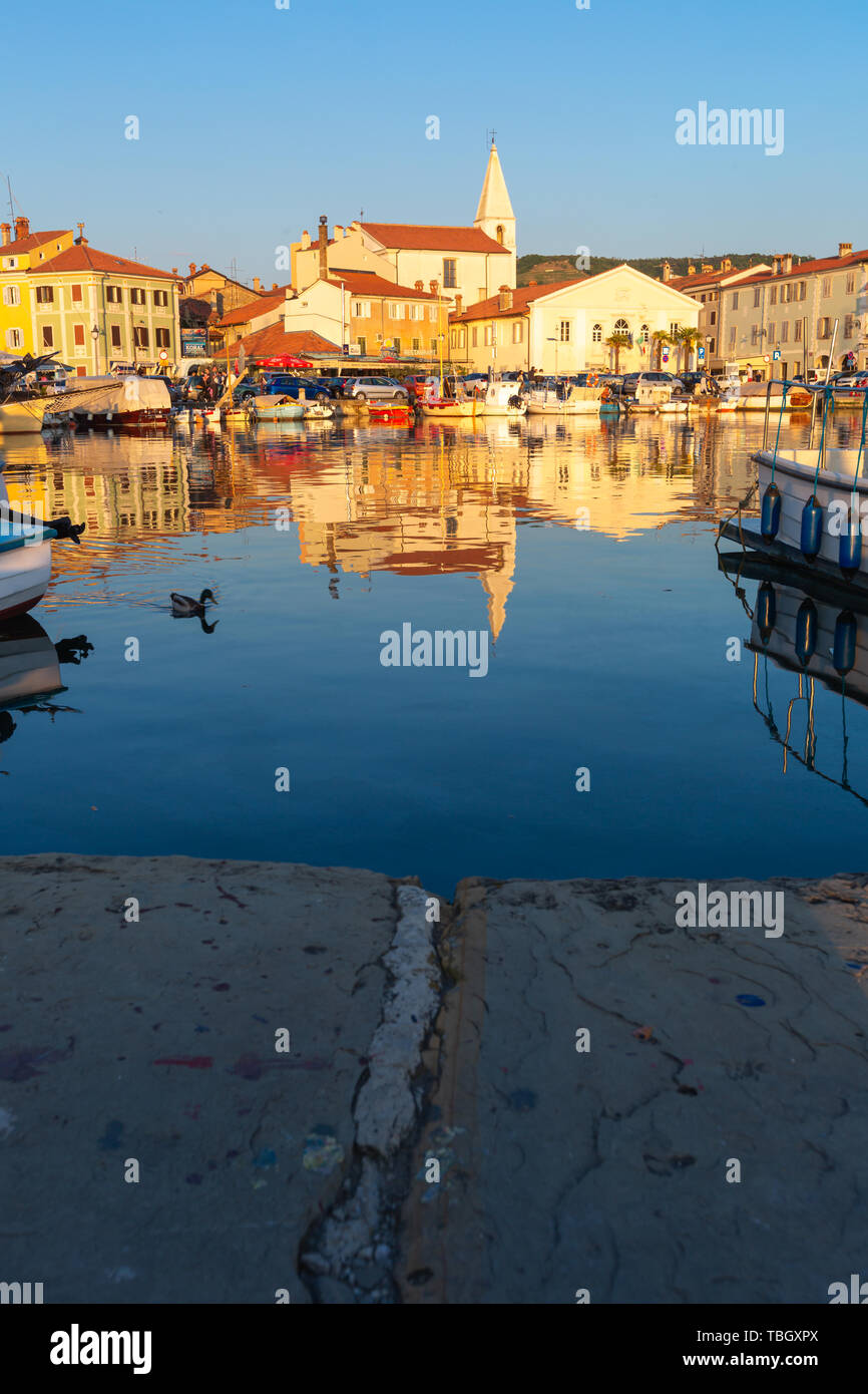 Izola, Slovenia - 1 Maggio 2019: panoramica del porto con barche e case vivacemente colorate sul lungomare al tramonto in Izola - Isola. Foto Stock