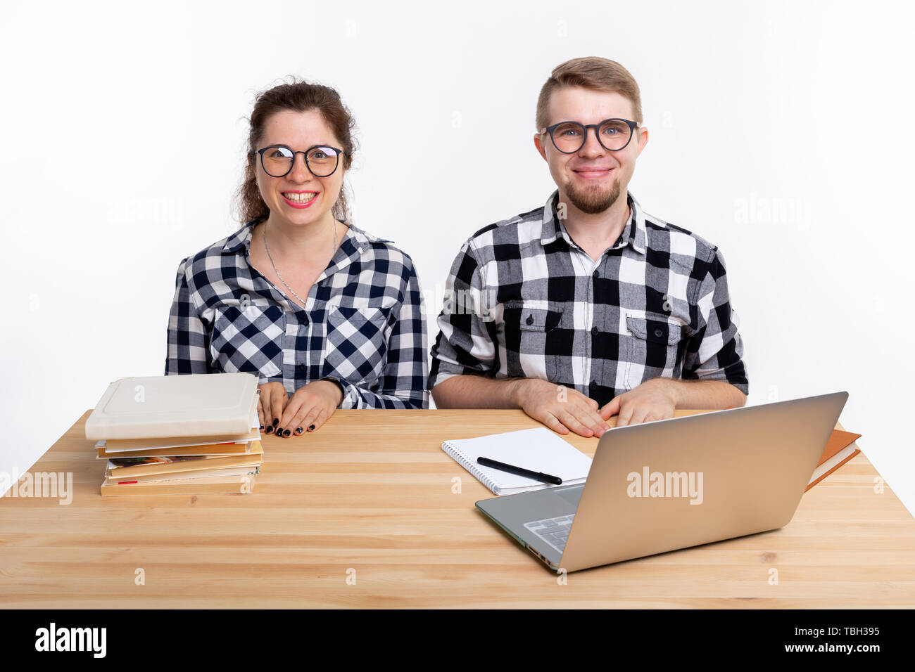 Le persone e il concetto di istruzione - due studenti vestito in plaid shirt seduti a un tavolo Foto Stock