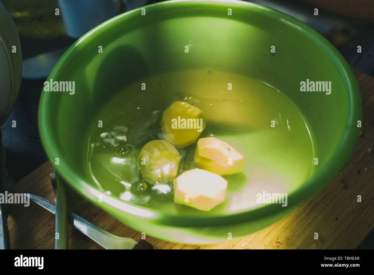 Patate sbucciate e giacciono in un verde ciotola con acqua. Foto Stock