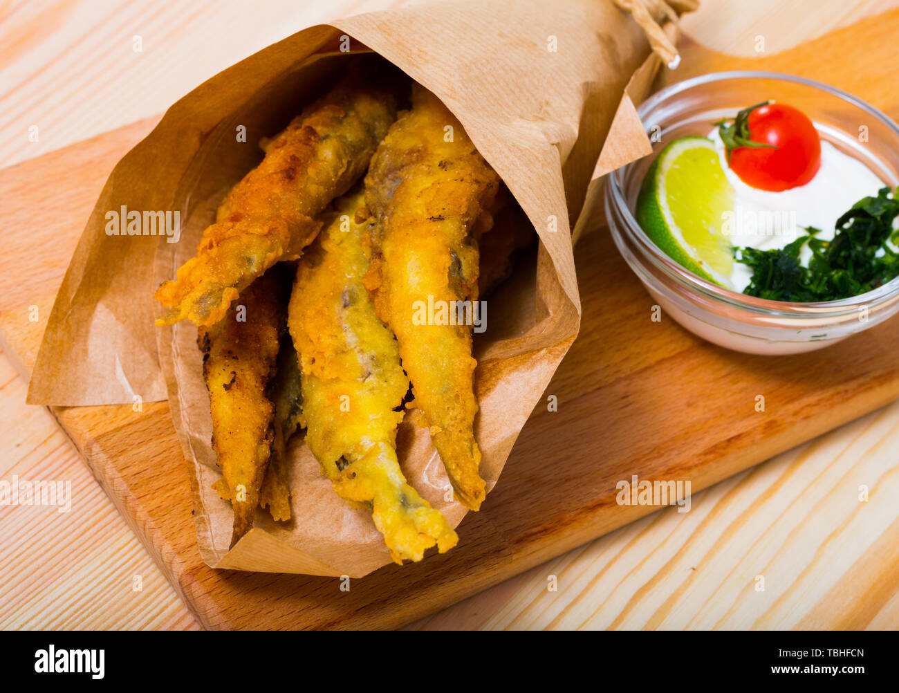 Pesce - patatine fritti in pastella di acciughe con la classica salsa di formaggio cremosa e verdi Foto Stock
