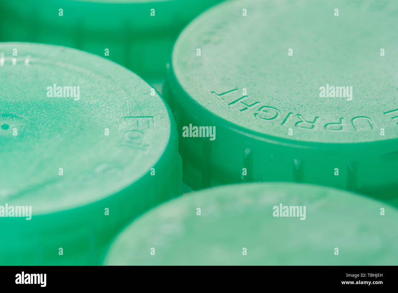 Close up di verde bottiglia di latte cime che mostra il concetto di riciclaggio o di bere il latte parzialmente scremato Foto Stock