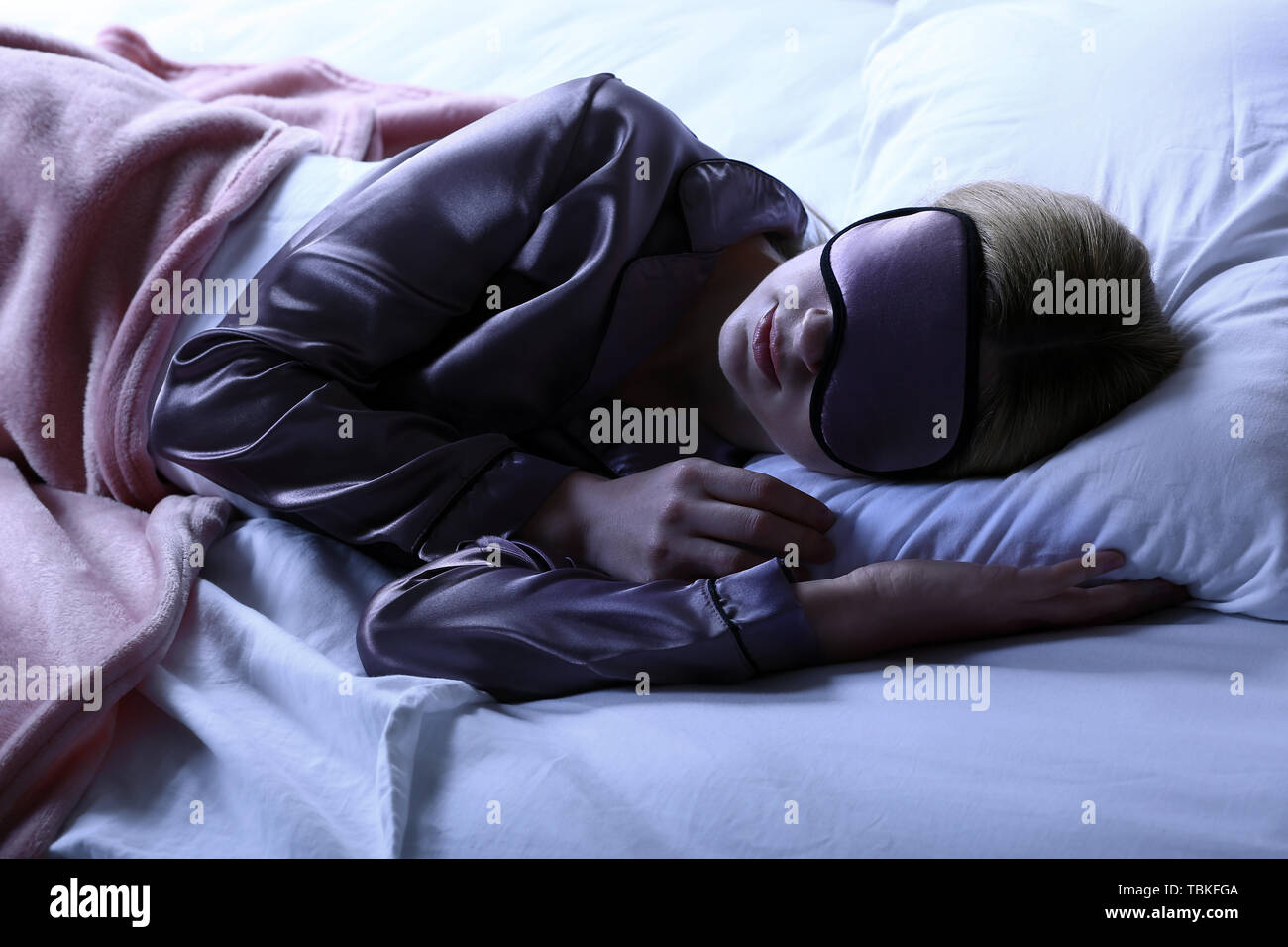 Donna con maschera dormire nel letto di notte Foto Stock