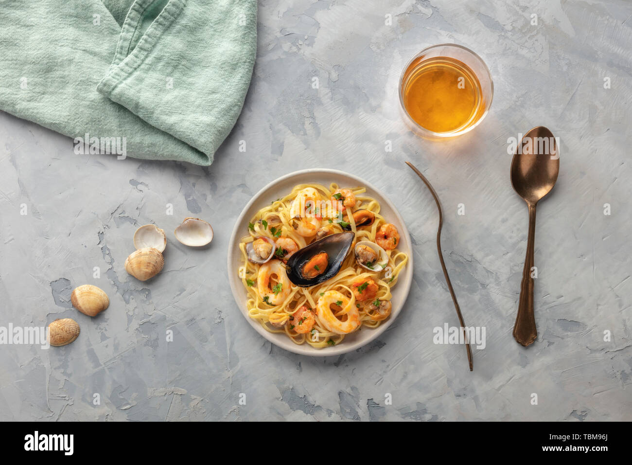 Piatti di pasta. Tagliolini con cozze, gamberi, vongole e anelli di totano, girato dalla parte superiore con un bicchiere di vino Foto Stock