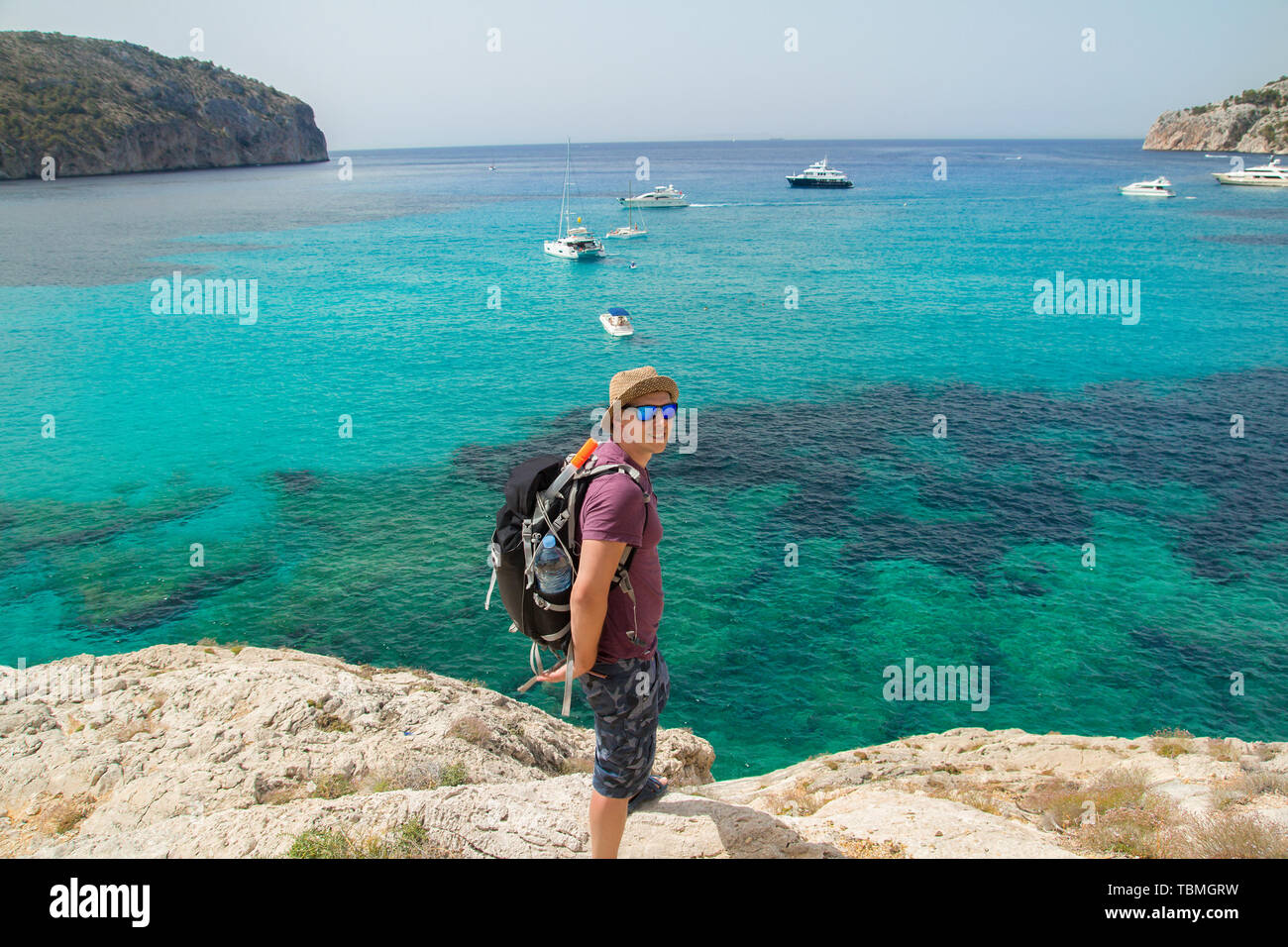 Uomo con zaino camminando sulle falesie sopra il mare Foto Stock