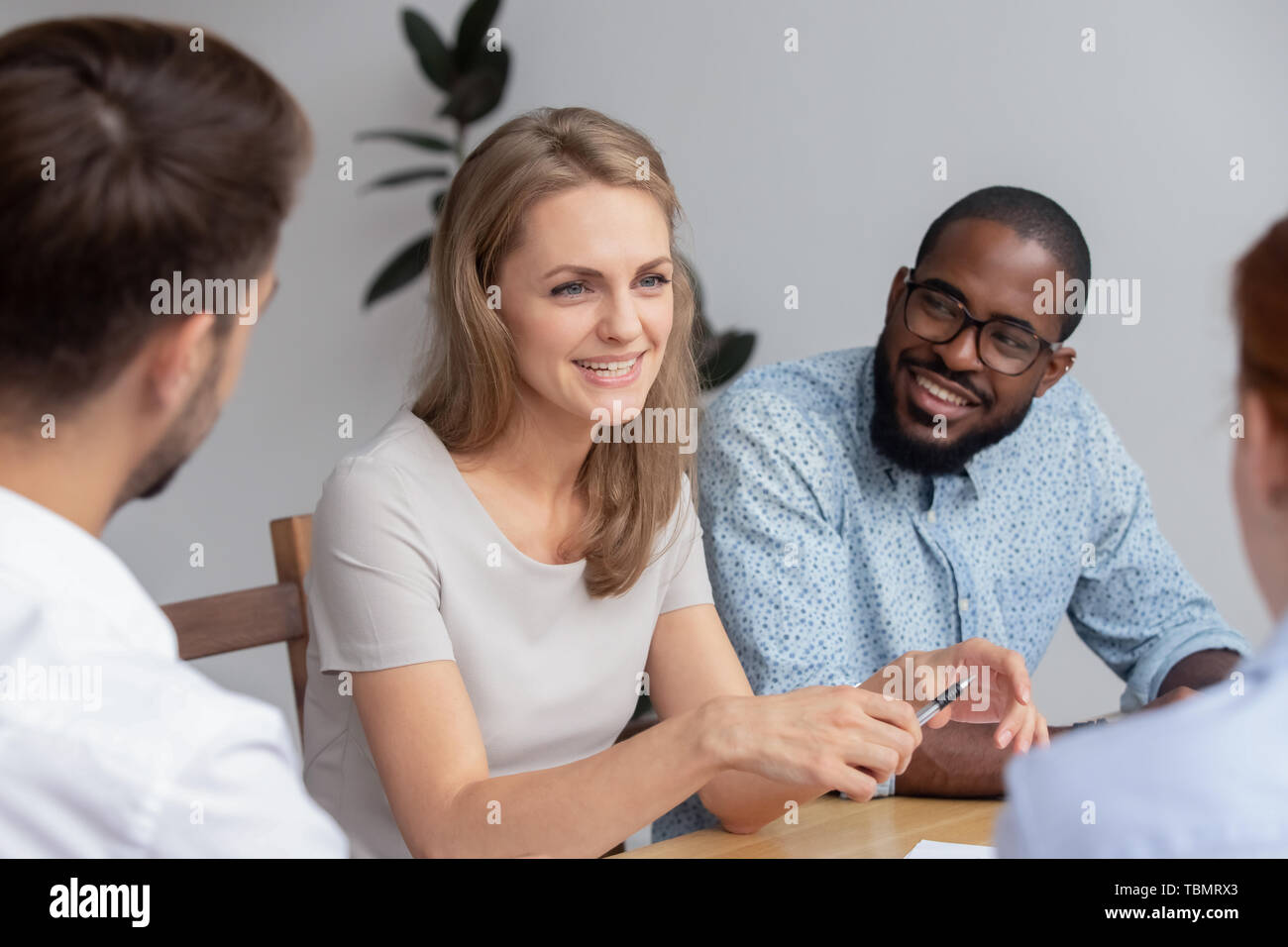Sorridenti giovane donna parlando con colleghi di lavoro Foto Stock