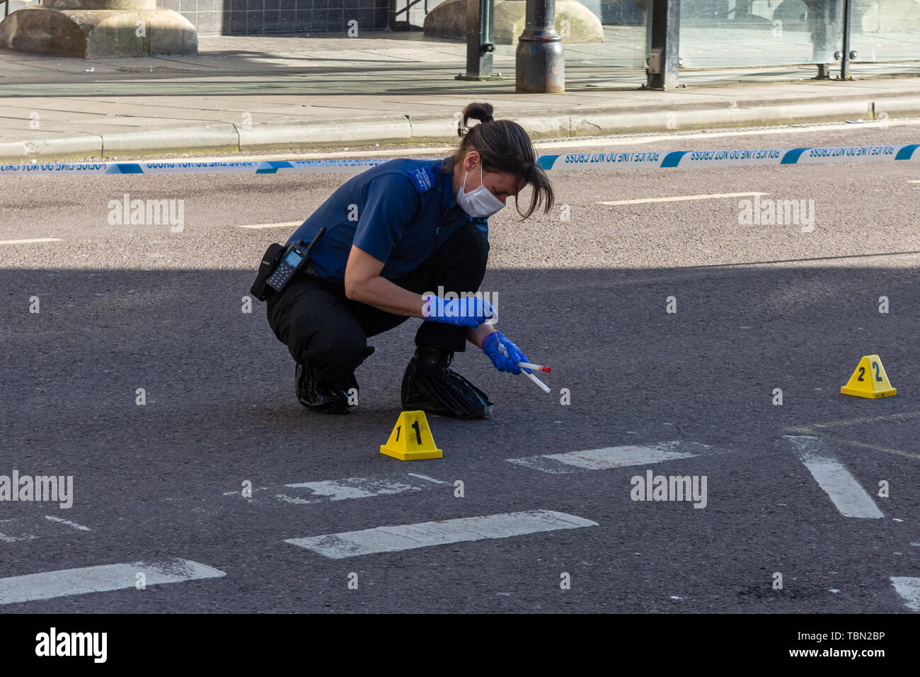 Un CSI per la polizia di Wiltshire con footcovers guanti e maschera facciale è utilizzando i tamponi per raccogliere prove del sangue dopo un incidente che coinvolga un coltello Foto Stock