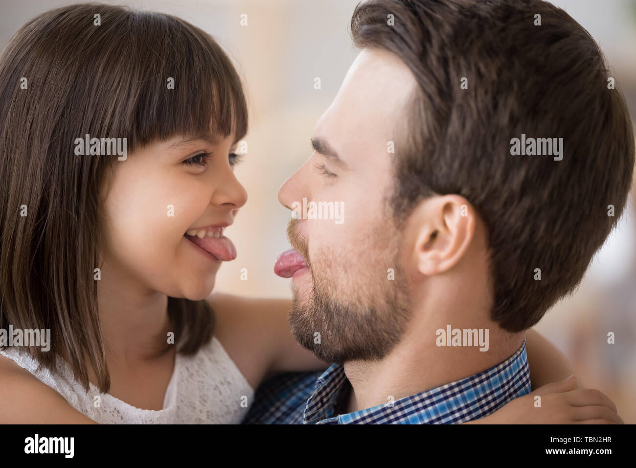 Giocoso papà e figlia giocare con il gioco che mostra le linguette Foto Stock