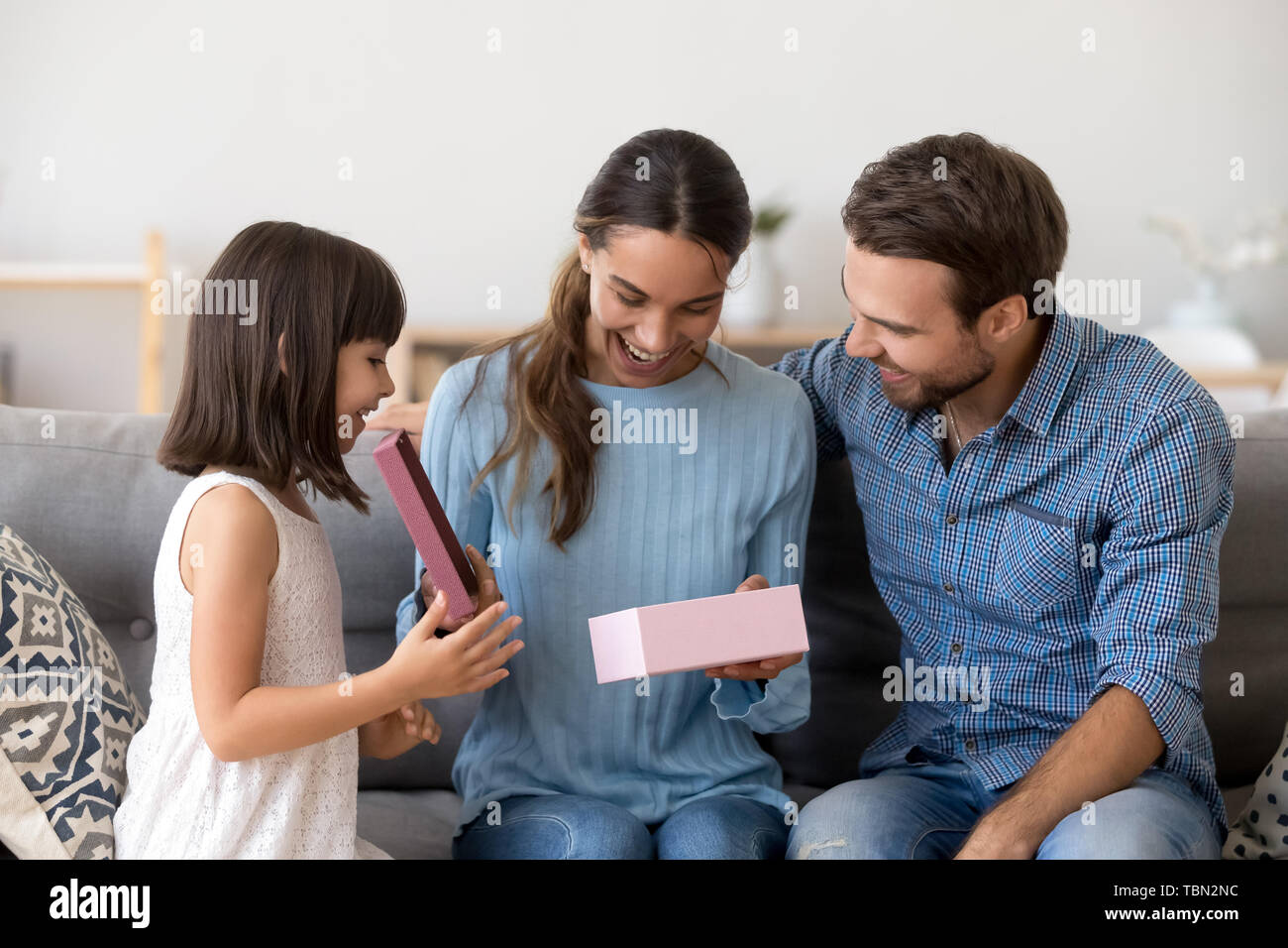 Emozionato mom aprire il regalo di compleanno con la figlia e suo marito Foto Stock