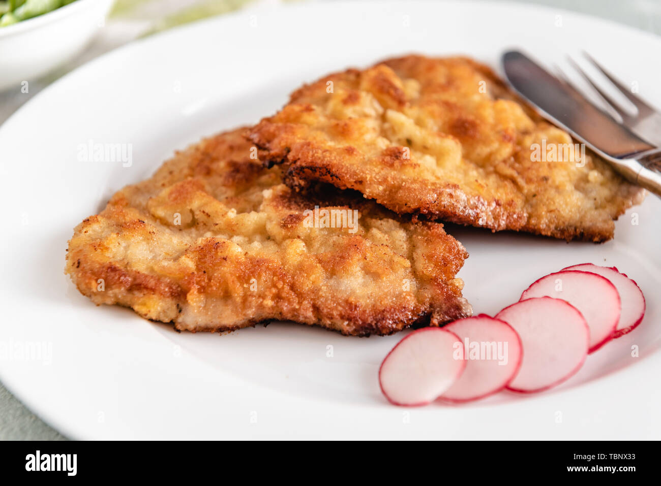 Maiale fritto chop nel pangrattato servita con ravanelli. Foto Stock