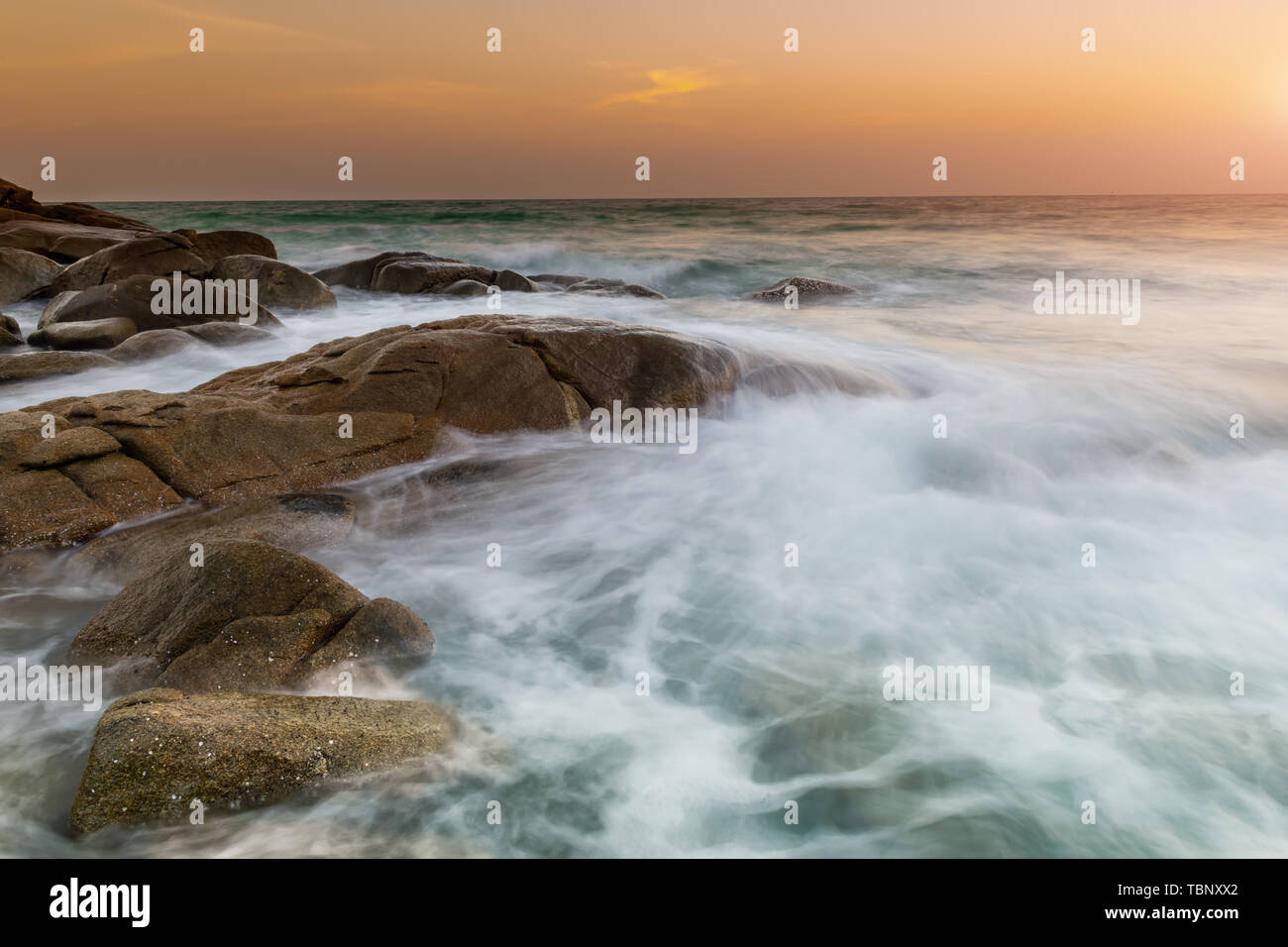 La roccia e liscia onde del mare nel tramonto foto con outdoor e bassa illuminazione scuro seascape. Foto Stock
