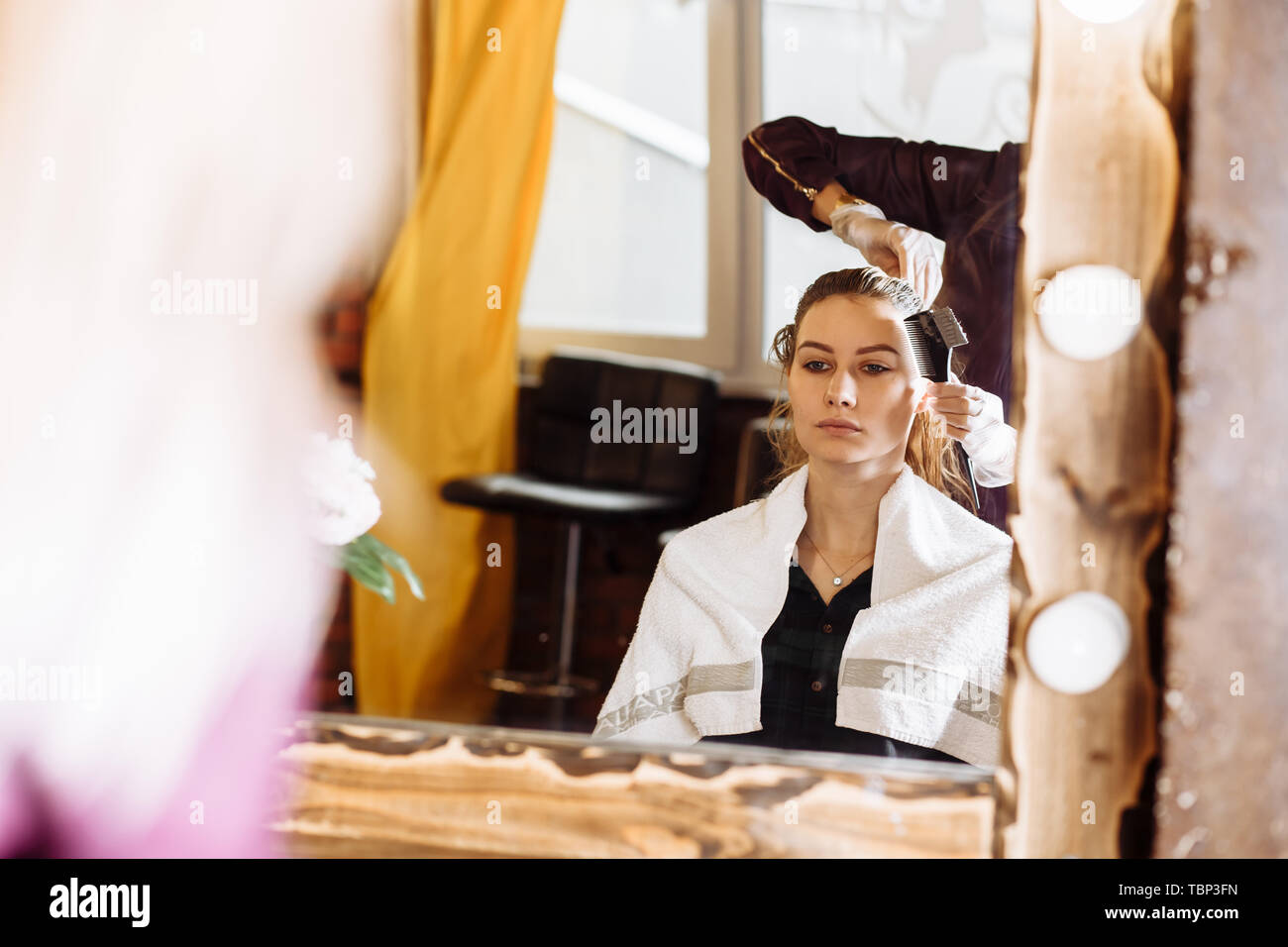 Il processo di trattamento di capelli, la colorazione dei capelli. Parrucchiere è morente capelli femmina. Bella client attraente seduti davanti ad uno specchio in elegante beaut Foto Stock