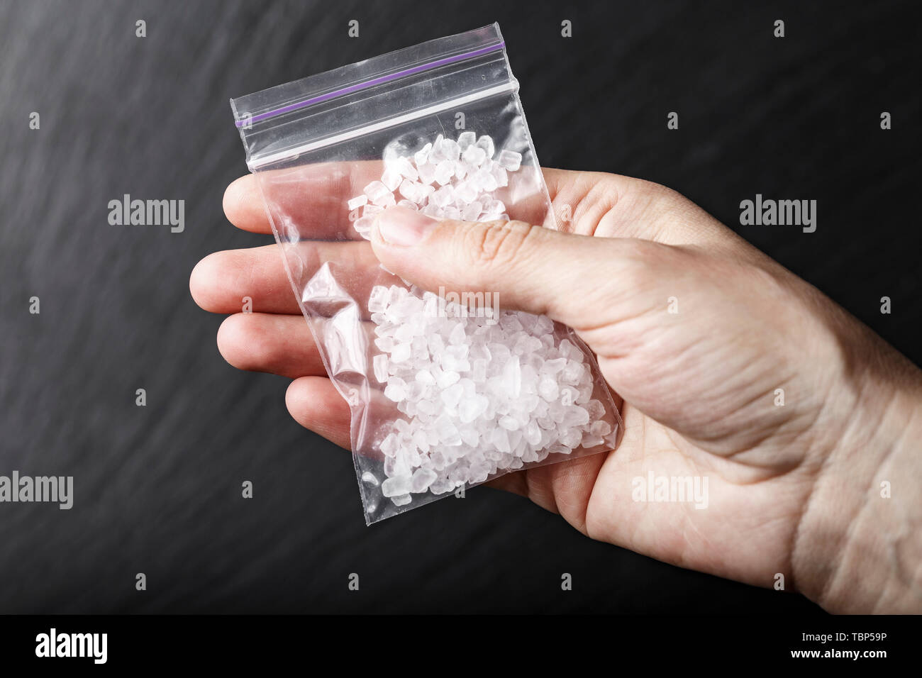 Cristalli bianchi farmaci metamfetamina in un sacchetto di plastica su uno sfondo nero Foto Stock