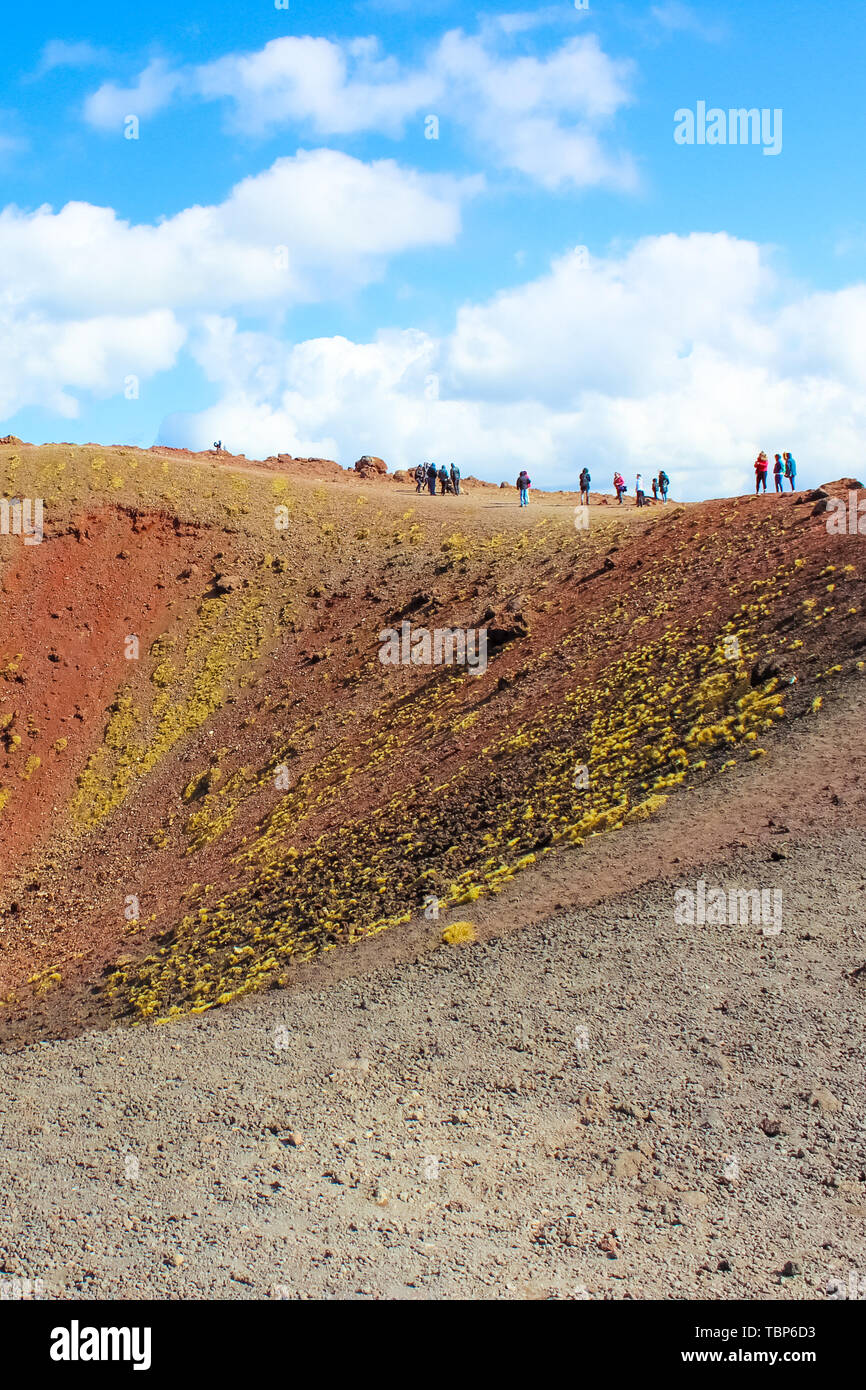 I turisti in piedi sul bordo dei crateri Silvestri sul Monte Etna in Sicilia italiano. Il fantastico paesaggio vulcanico è una popolare destinazione turistica. Fotografia verticale. Foto Stock