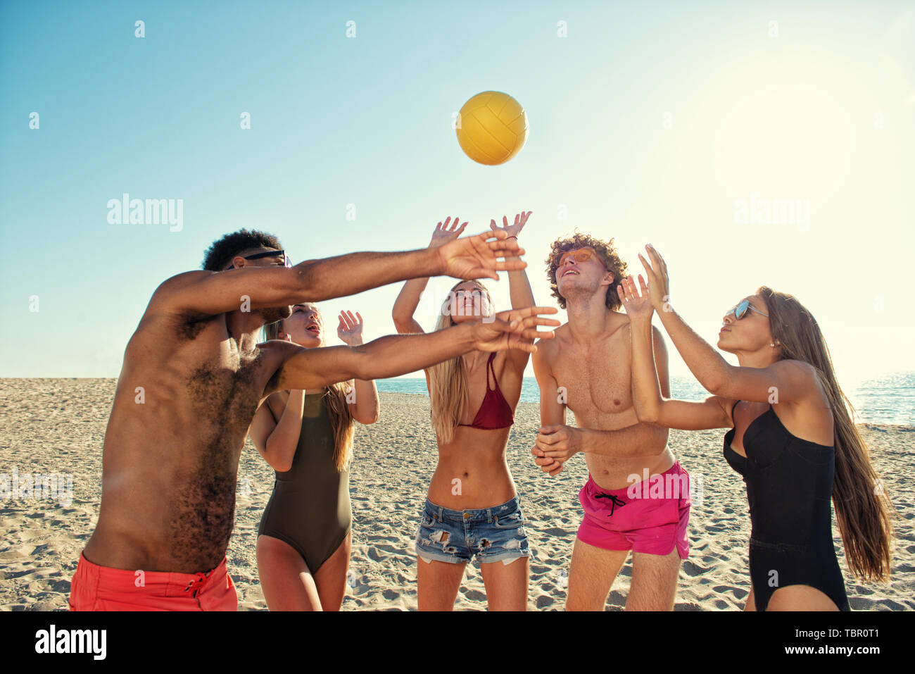 Gruppo di amici a giocare a beach volley in spiaggia Foto Stock