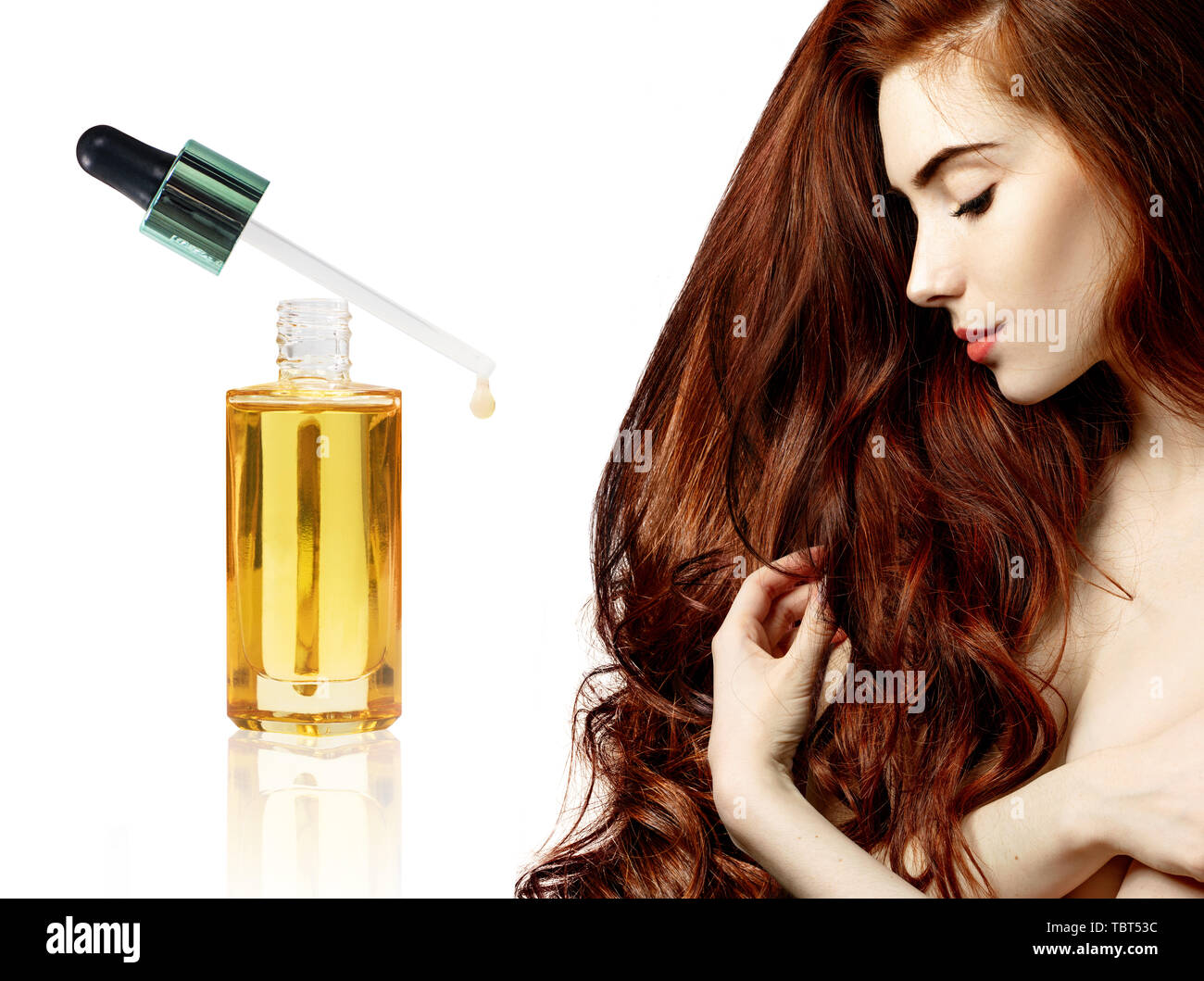 Redheaded donna vicino goldden bottiglia con olio. Foto Stock