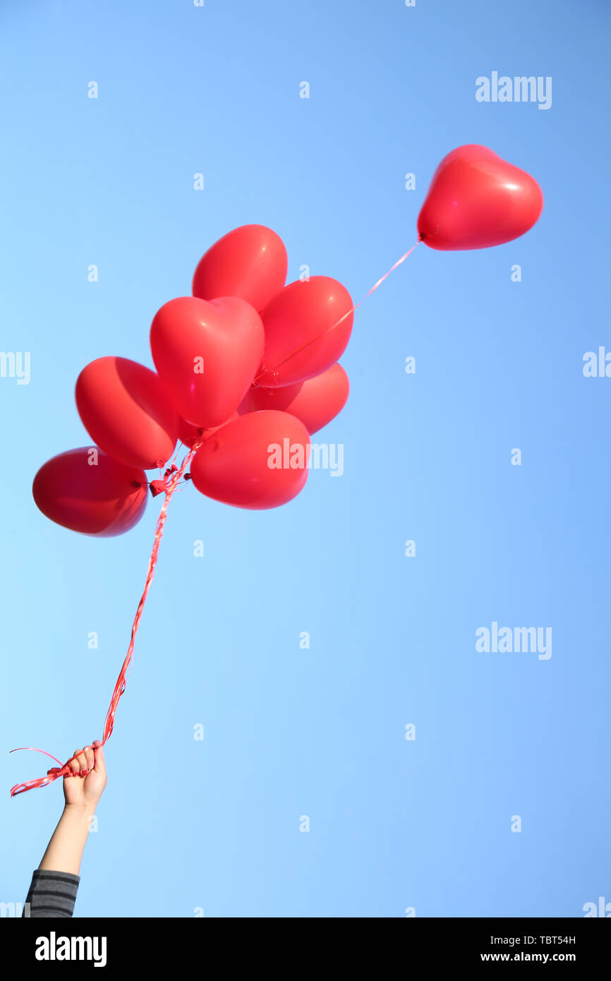 Mano che tiene un palloncino rosso galleggianti in aria Foto stock - Alamy