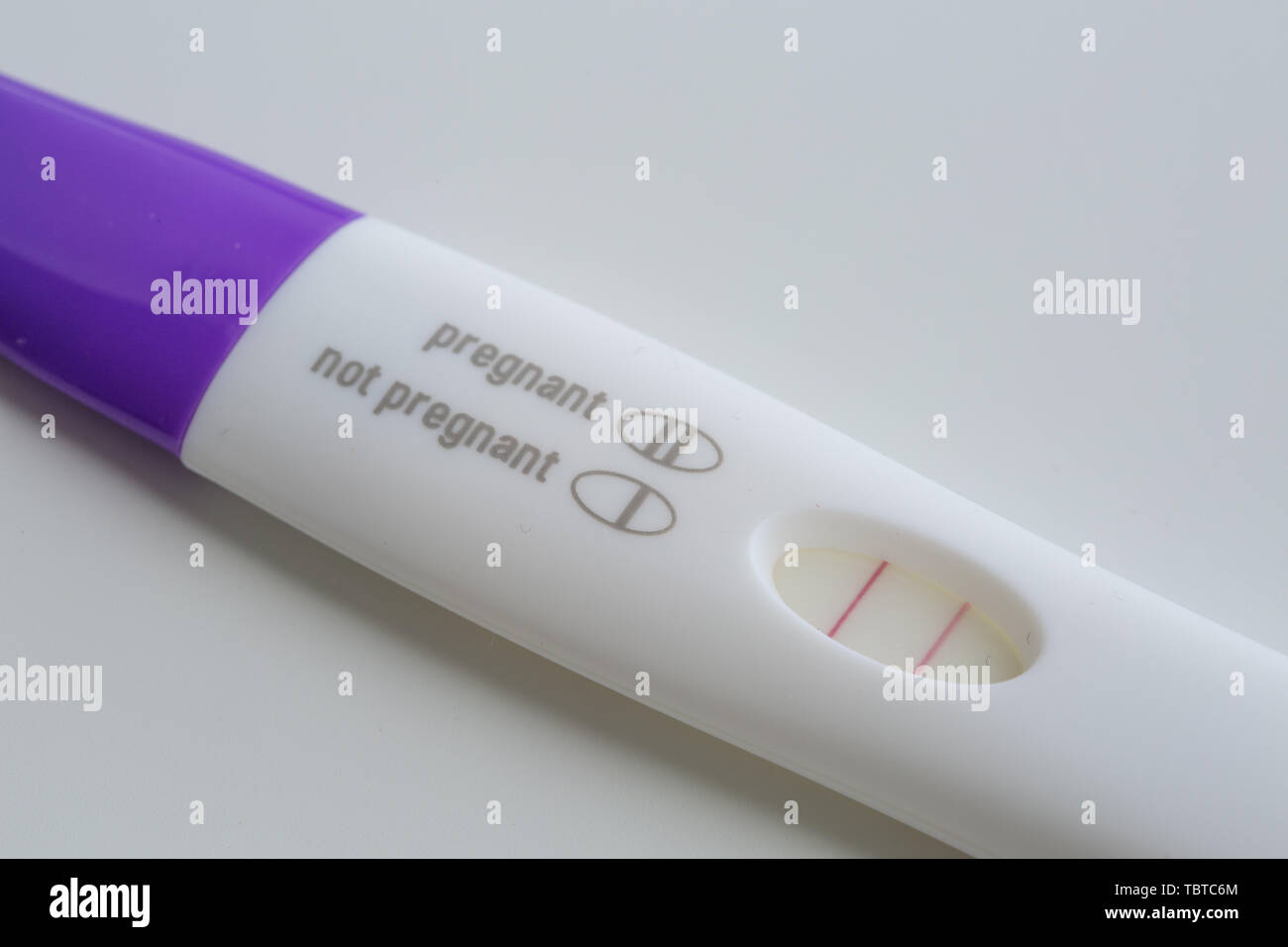 Positive le prime fasi della gravidanza di carta di prova test di gravidanza stick sfondo bianco Foto Stock