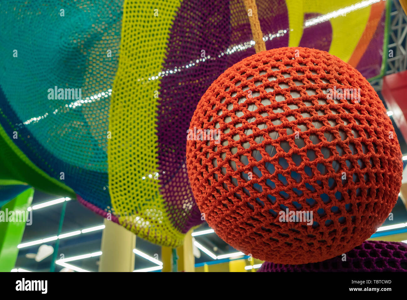 Sfera di gomma, ricoperti con un rosso maglia di vimini. Texture astratta di multi-colore di tessuti. Creative sfondo vintage Foto Stock
