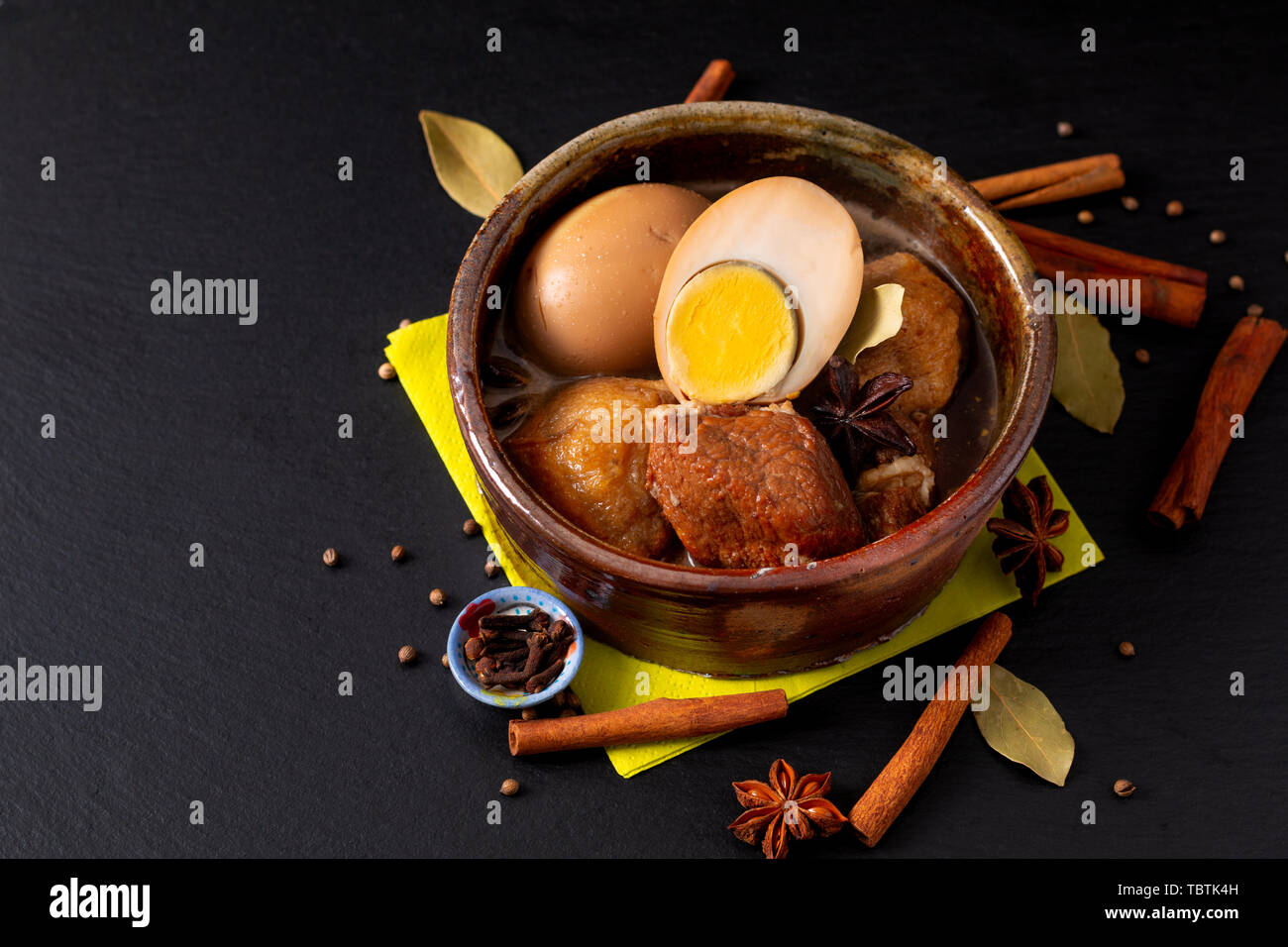 Concetto di alimentare la cucina tailandese pancetta di maiale e uova con cinque spezie fragranti stufare Moo Palo su ardesia nera con scheda spazio di copia Foto Stock