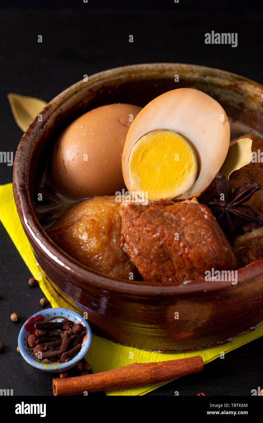 Concetto di alimentare la cucina tailandese pancetta di maiale e uova con cinque spezie fragranti stufare Moo Palo su ardesia nera con scheda spazio di copia Foto Stock