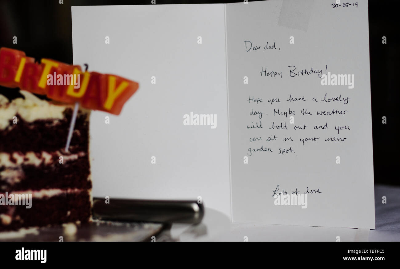Colorato BUON COMPLEANNO candele, rimasto fetta di torta rossa del velluto con un biglietto di auguri Foto Stock
