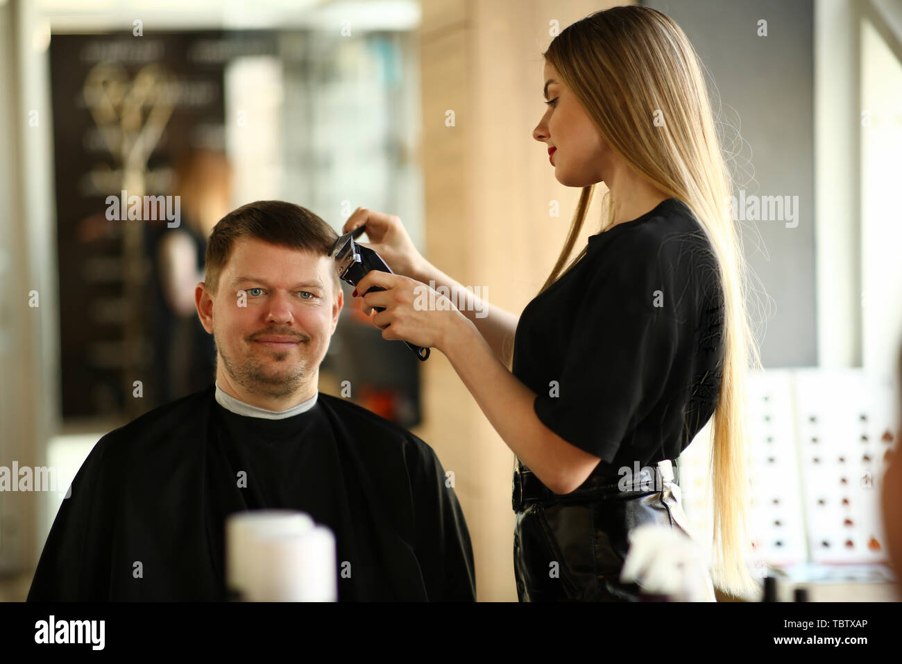 Donna Parrucchiere rendendo taglio di capelli rasoio per uomo. Parrucchiere  femmina Styling taglio di capelli da rasoio elettrico. Client maschio di  ottenere l'acconciatura in Barberia. Pro Foto stock - Alamy