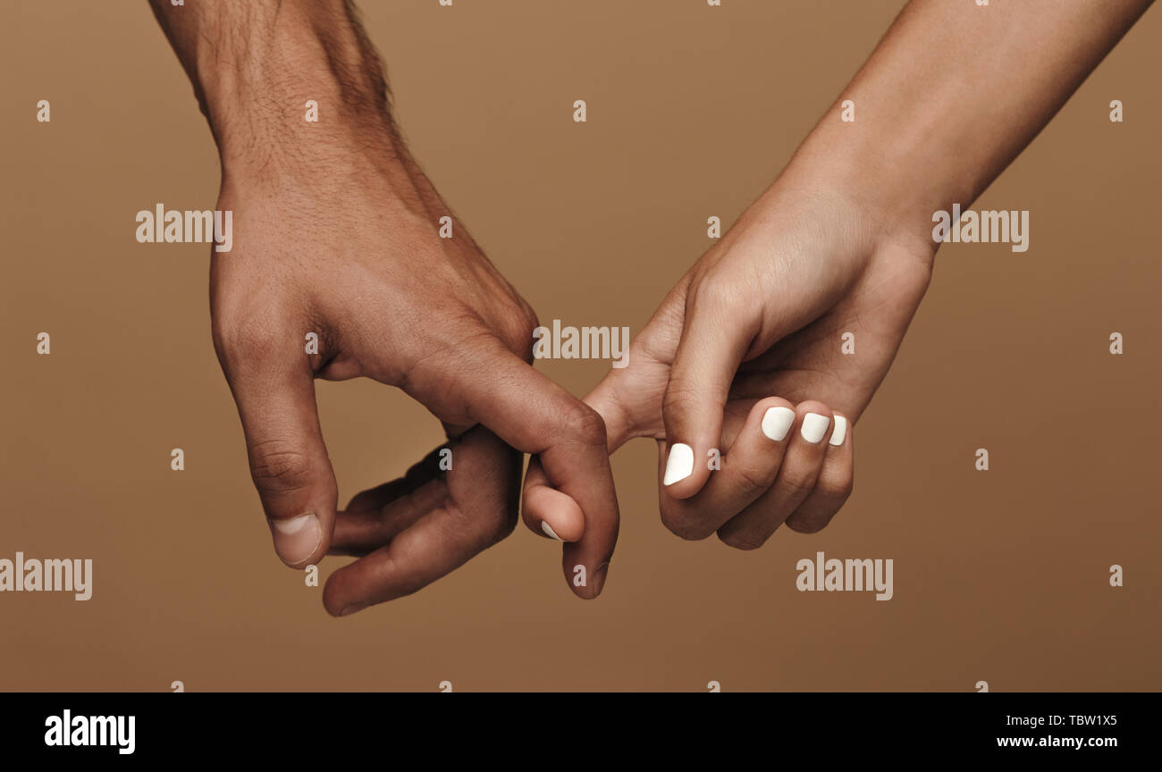 Close up di un giovane che collegano le dita indice. L uomo e la donna nella carità che unisce le dita indice contro lo sfondo marrone Foto Stock