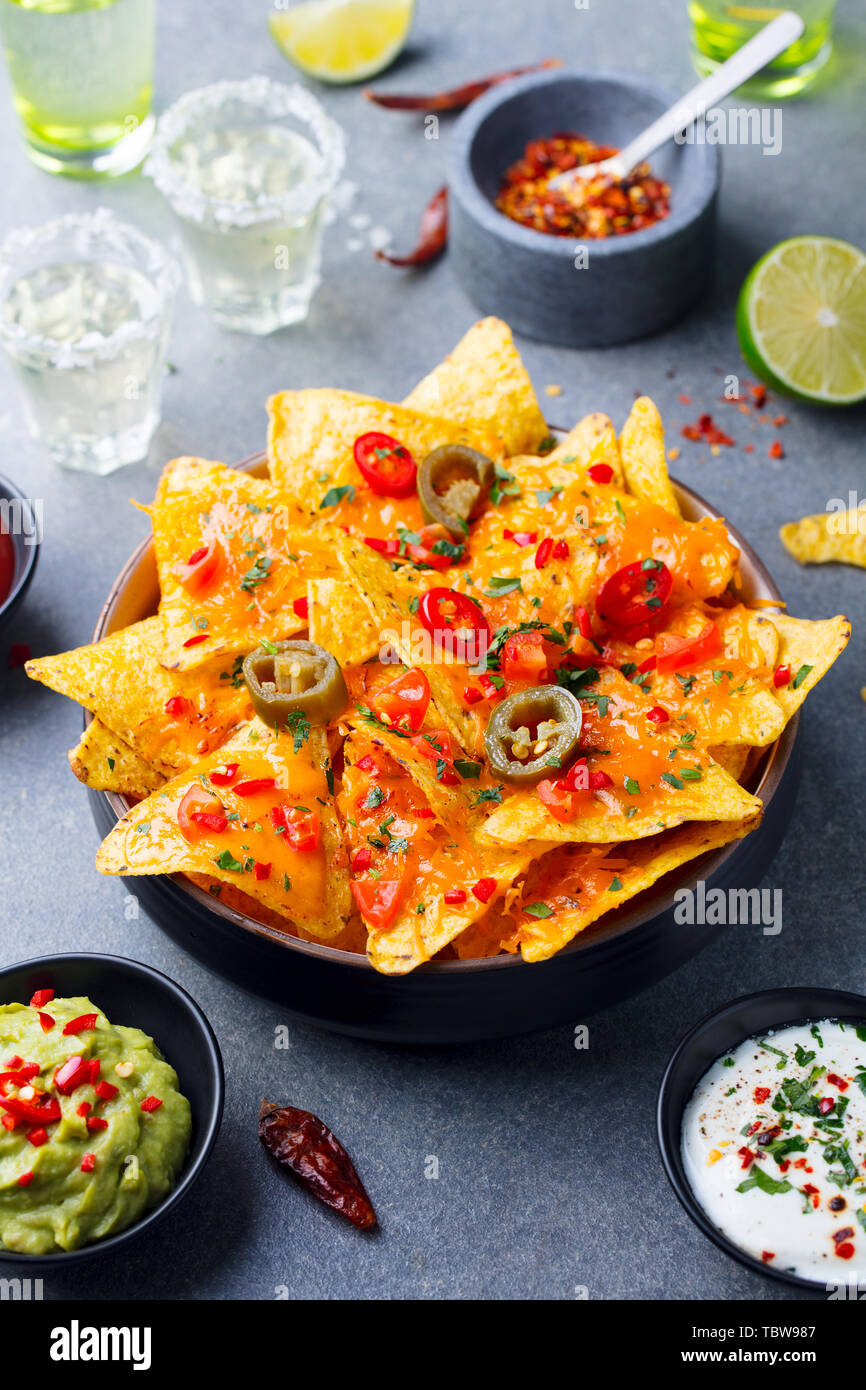 Nachos chip con il formaggio fuso e salse varietà in vaso nero. Grigio pietra dello sfondo. Foto Stock