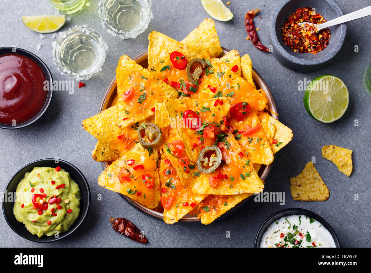 Nachos chip con il formaggio fuso e salse varietà in vaso nero. Vista dall'alto. Foto Stock