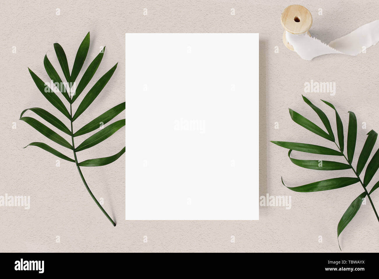 Nozze femminile stationery mock-up scena. Bigliettino vuoto, Verde foglie di palmo e nastro di seta sulla trama beige sfondo tabella, tropic estate st Foto Stock