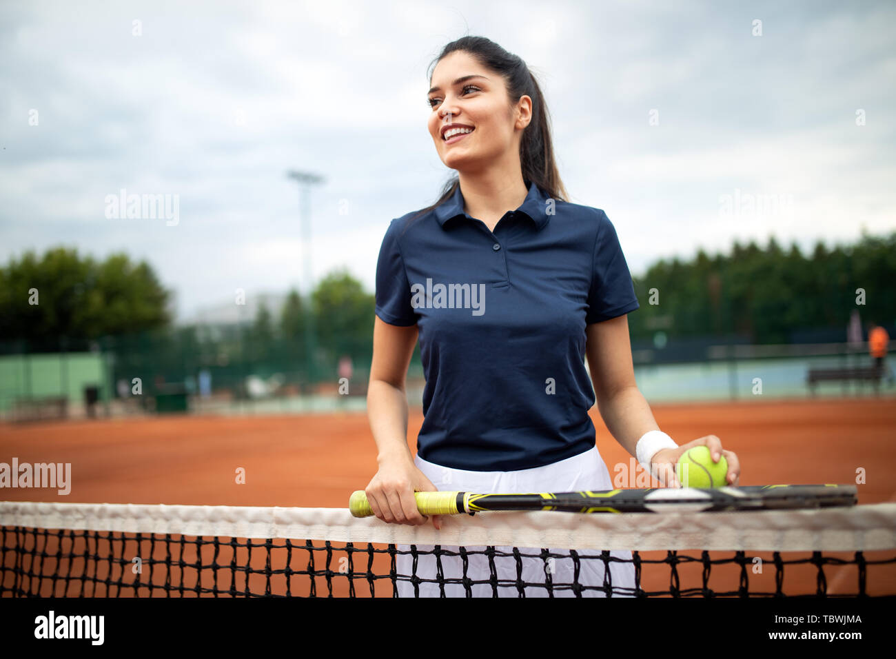 Ritratto di donna forte giocando a tennis sui campi da tennis esterni Foto Stock