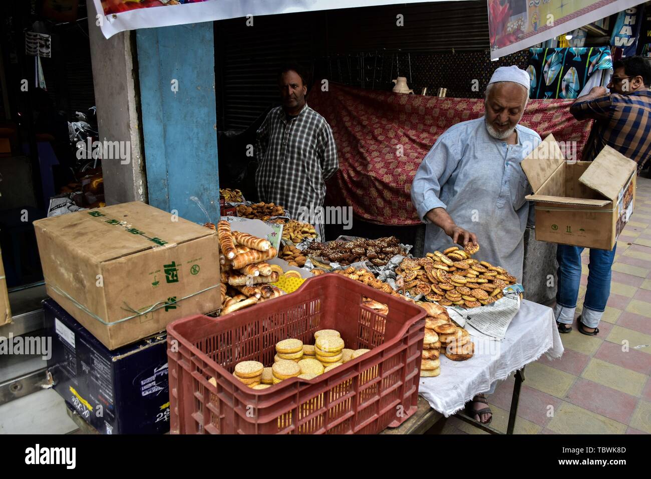 Un bottegaio regola articoli da forno in anticipo della festa musulmana Eid al-Fitr ad un mercato locale a Srinagar. Mercati di tutto il mondo musulmano testimonianza un enorme centro commerciale rush in preparazione per l'Eid al-Fitr, una festa che segna la fine del musulmano il mese di digiuno del Ramadan. Foto Stock
