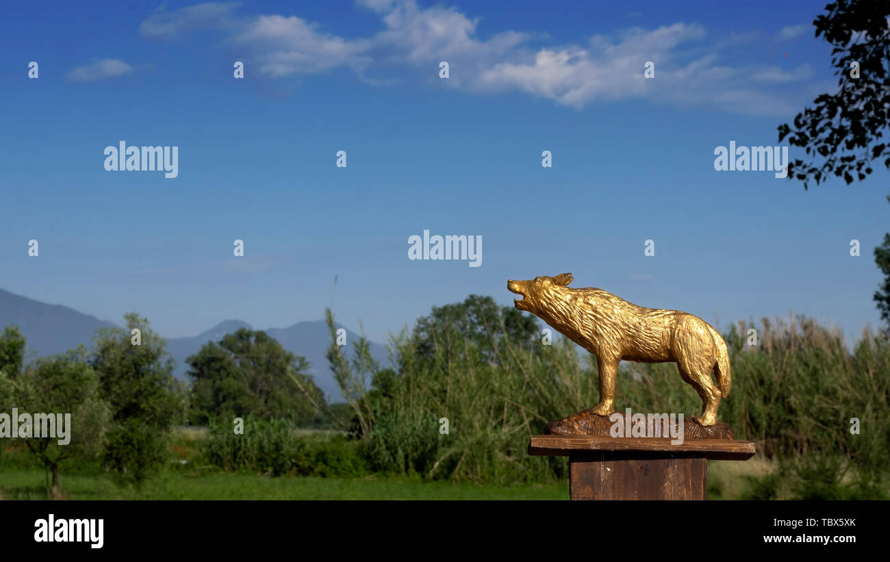 Golden wolf figurina, simbolo di Roma, Italia. Paesaggio italiano dietro. Foto Stock