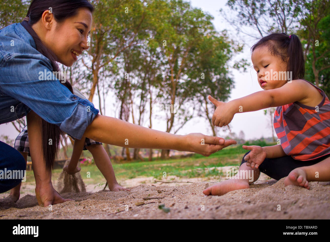 Ritratto di stile di vita mamma figlio e figlia gioca con la sabbia, Funny famiglia asiatica in un parco ad alta risoluzione galleria dell'immagine. Foto Stock