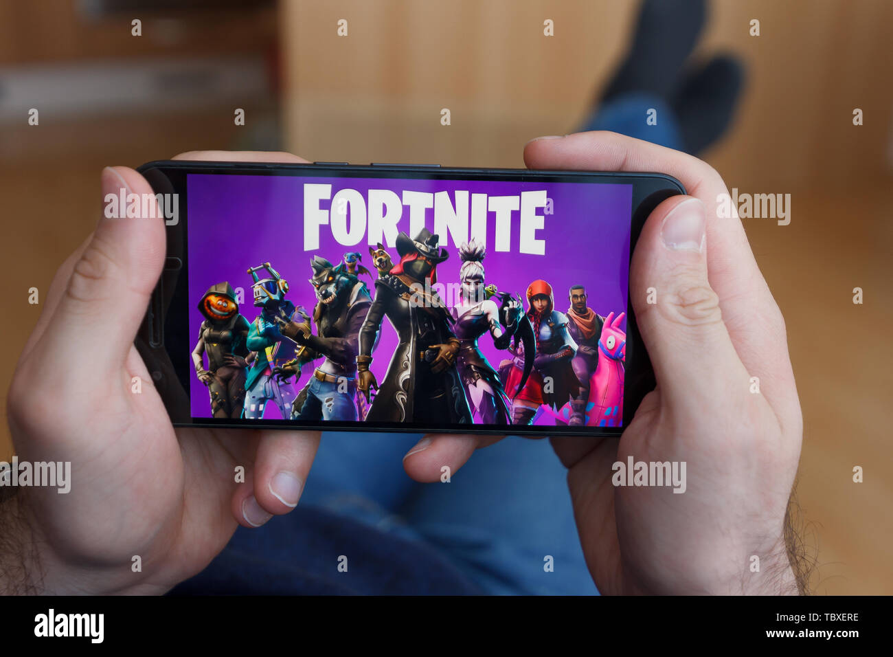 LOS ANGELES, CALIFORNIA - Giugno 3, 2019: Uomo sdraiato tenendo un smartphone e giocare il gioco Fortnite sullo schermo dello smartphone. Un esempio illustrativo editori Foto Stock