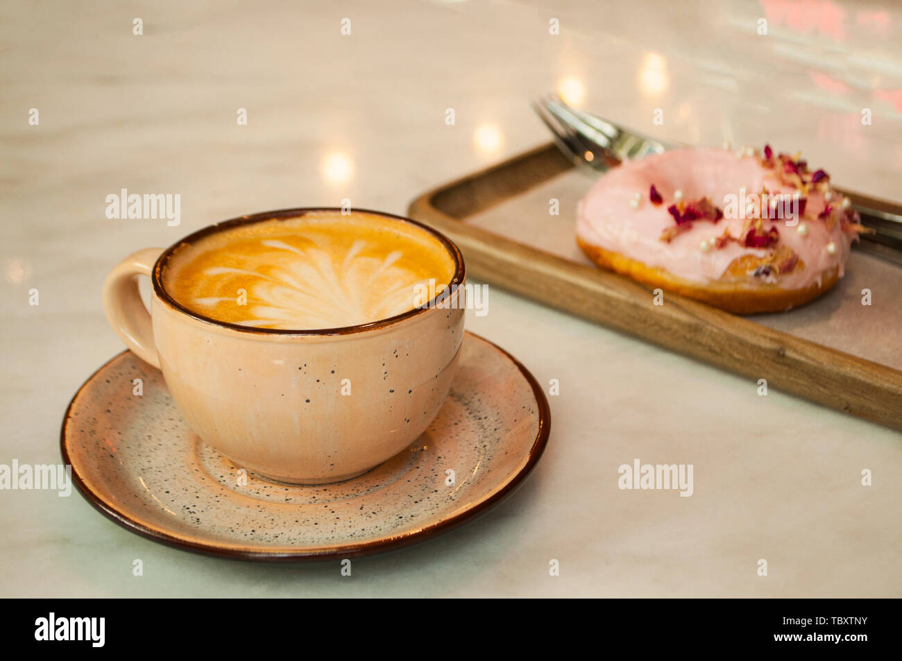Tazza di cappuccino con belle latte art e la ciambella in una tabella in un cafe'. Foto Stock