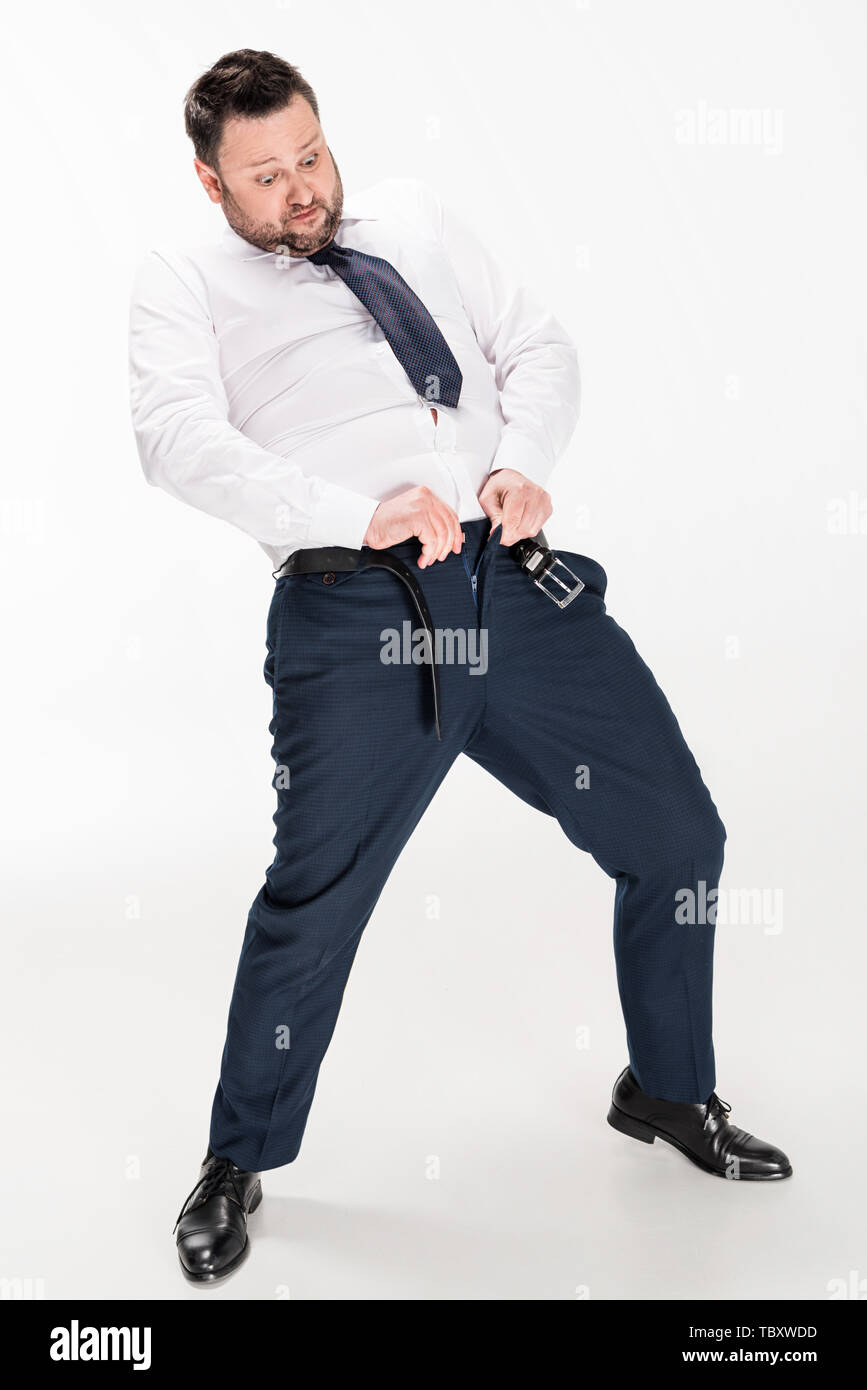 Il sovrappeso uomo in abbigliamento formale mettendo su i pantaloni stretti su bianco Foto Stock