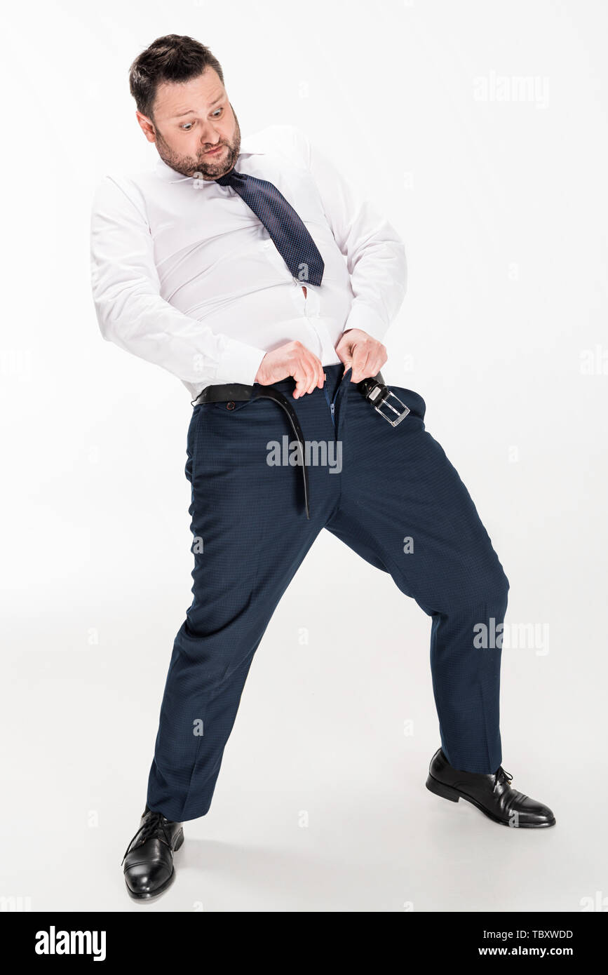 Il sovrappeso uomo in abbigliamento formale mettendo su i pantaloni stretti  su bianco Foto stock - Alamy