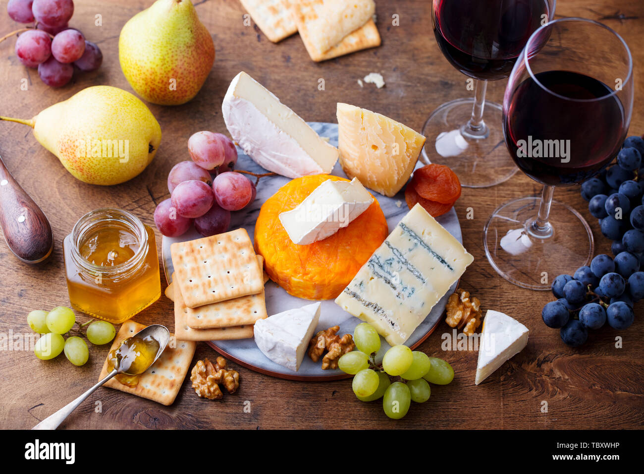 Assortimento di formaggi, uve da vino rosso in bicchieri. Sfondo di legno. Vista dall'alto. Foto Stock