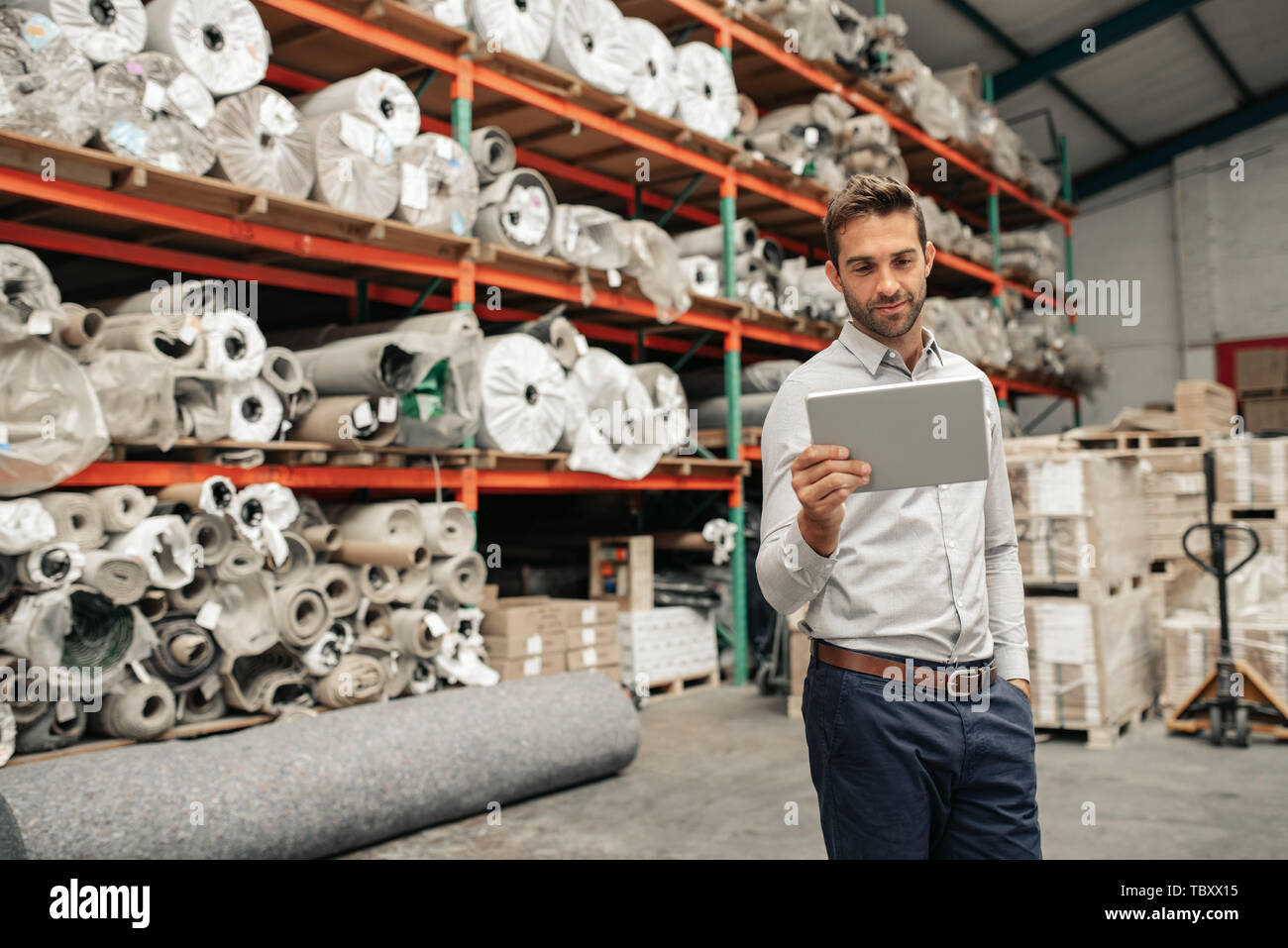 Sorridente warehouse manager utilizzando una tavoletta digitale durante il controllo del magazzino Foto Stock