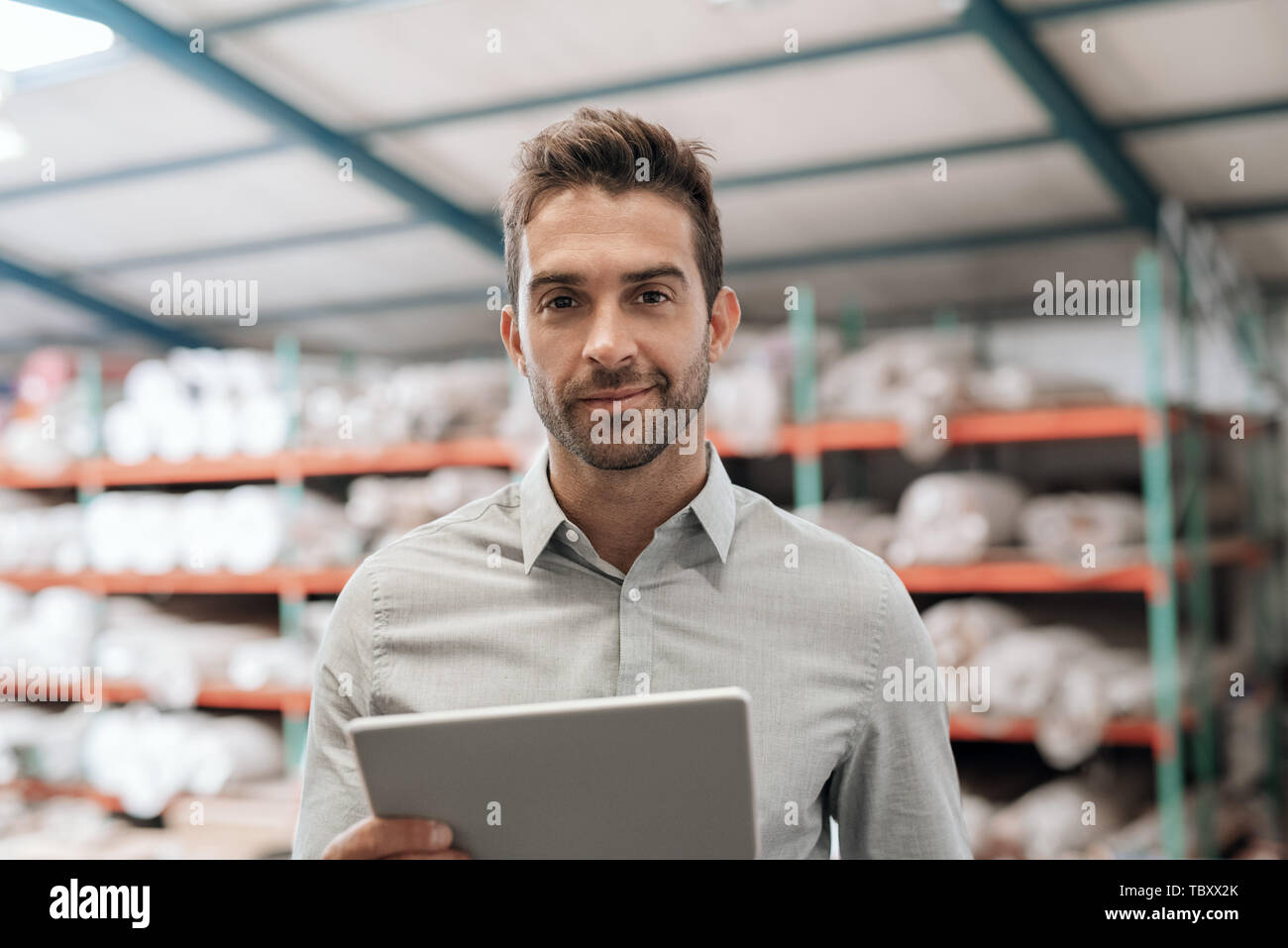 Responsabile magazzino sorridere mentre utilizzando una tavoletta digitale Foto Stock