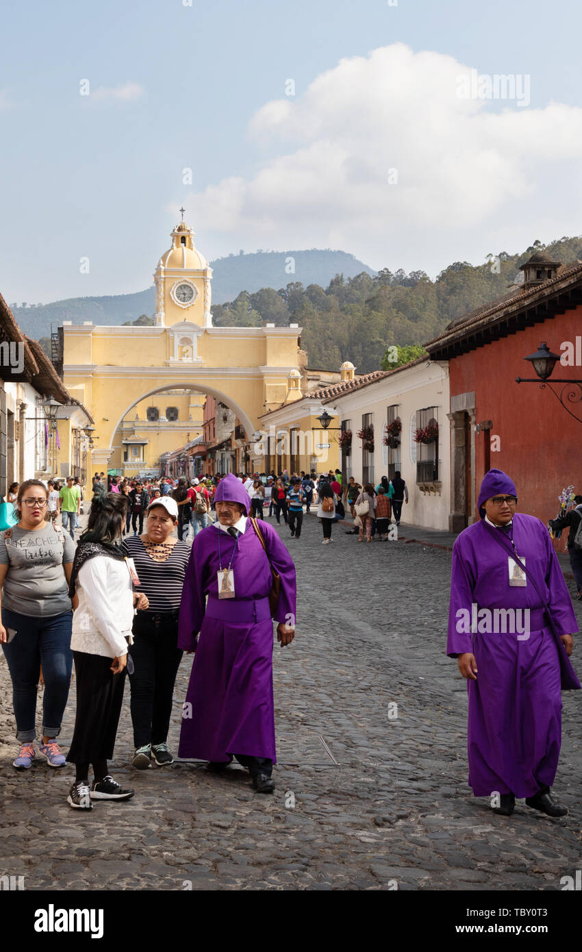 Antigua Guatemala la settimana santa - la popolazione locale nei tradizionali costumi religiosi in strada, con Santa Catalina arch, Antigua Guatemala America Latina Foto Stock