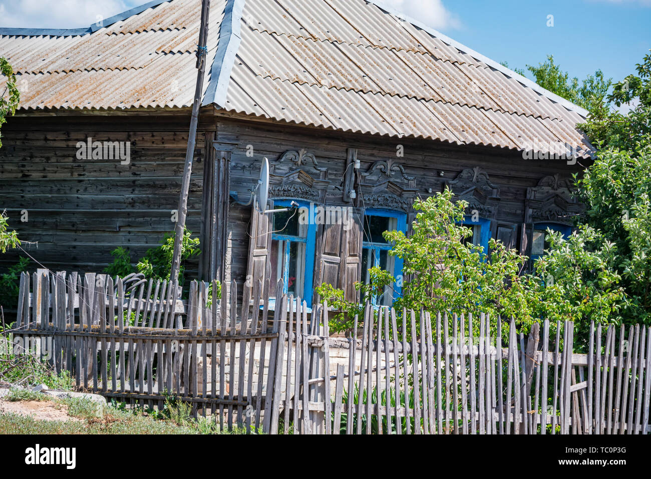 Vista della vecchia casa in legno in estate nel paese con una parabola satellitare Foto Stock