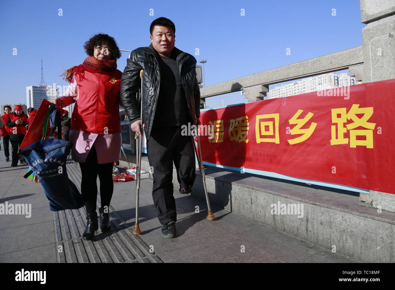 Il 21 gennaio 2017, il Festival di primavera ha iniziato a. Servizio di volontariato e riscaldare le attività sono state svolte a Zhengzhou stazione ferroviaria. Nel vento freddo, volontari inviato parole di benedizione, Festival di Primavera baciata e acqua calda al ritorno di passeggeri. Una mezza età volontario è stato entusiasta per aiutare il sig. Qiao, una persona disabile con mobilità limitata, acquistare biglietti e escort nella stazione. Foto Stock