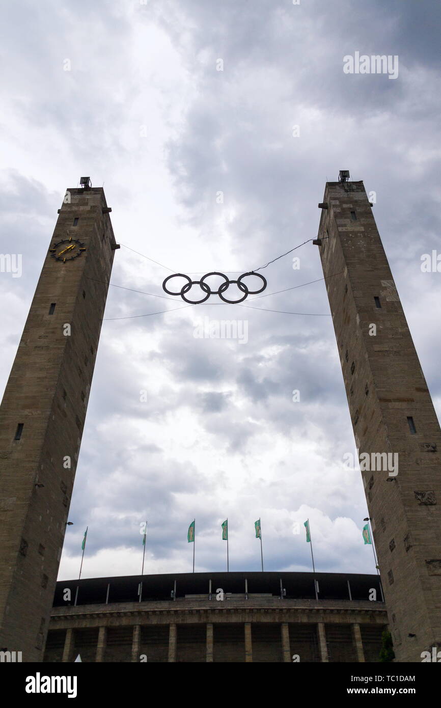 Anelli olimpici simbolo appesa sopra lo stadio olimpico da 1936 a Berlino, Germania, nuvole drammatico sfondo cielo Foto Stock