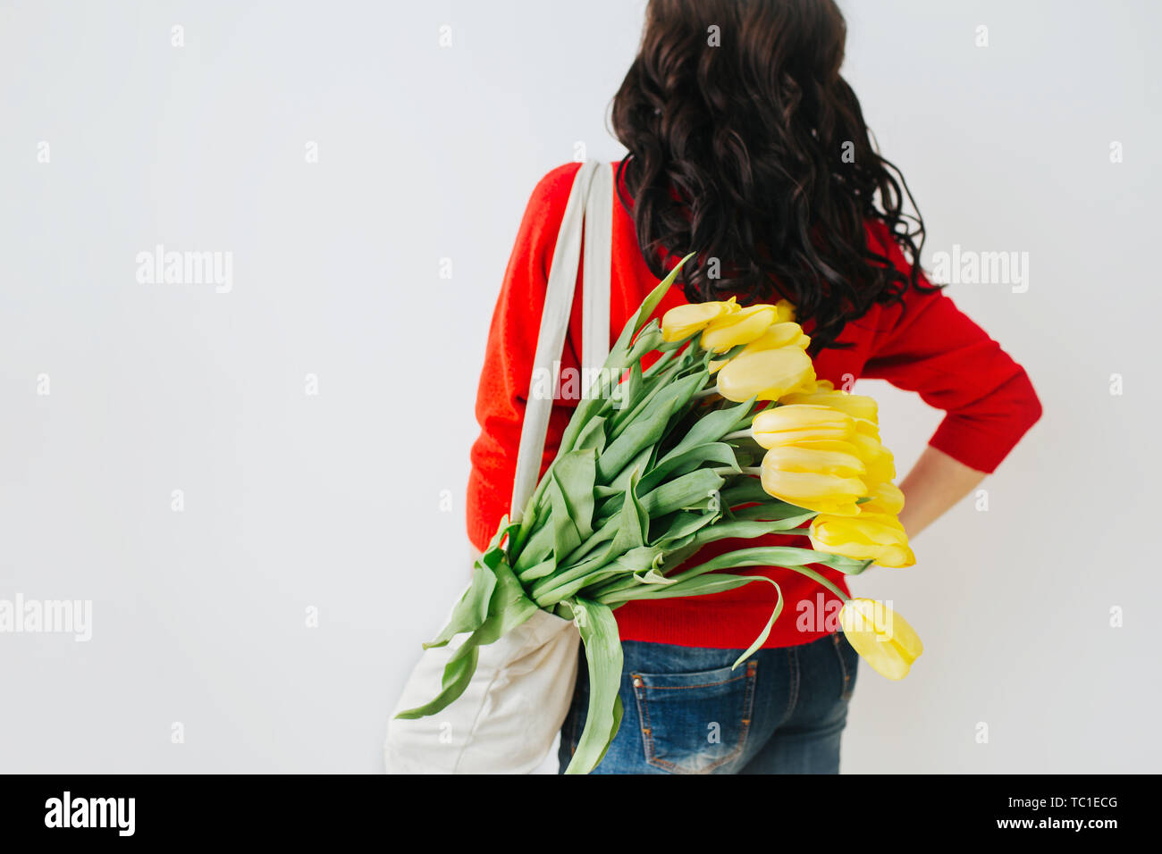 Giovane Donna con fiori gialli in lino eco borsa su una spalla. Girando intorno su uno sfondo bianco Foto Stock
